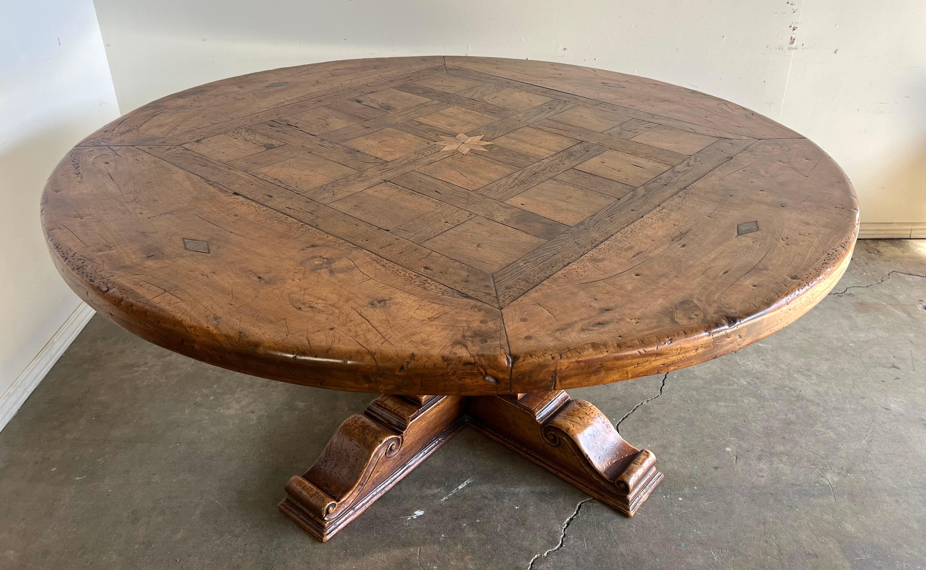 19th century large rustic inlaid dining table.  It features a thick tabletop with visible wood grain patterns and a geometric inlay design.  The edge of the tabletop is slightly beveled, giving it a smooth and rounded appearance.

The base of the
