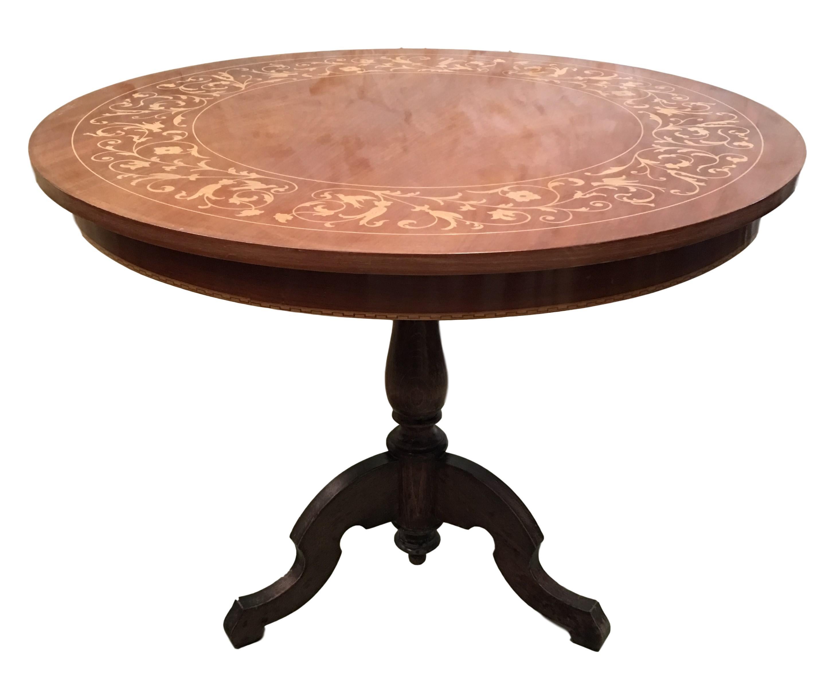 This Italian round pedestal wooden table from the mid to late 19th century features an exquisite floral and birds parquetry motif inlay on the top, surrounded by a sectional motif in the surround. The apron echoes the decorative banding found on the