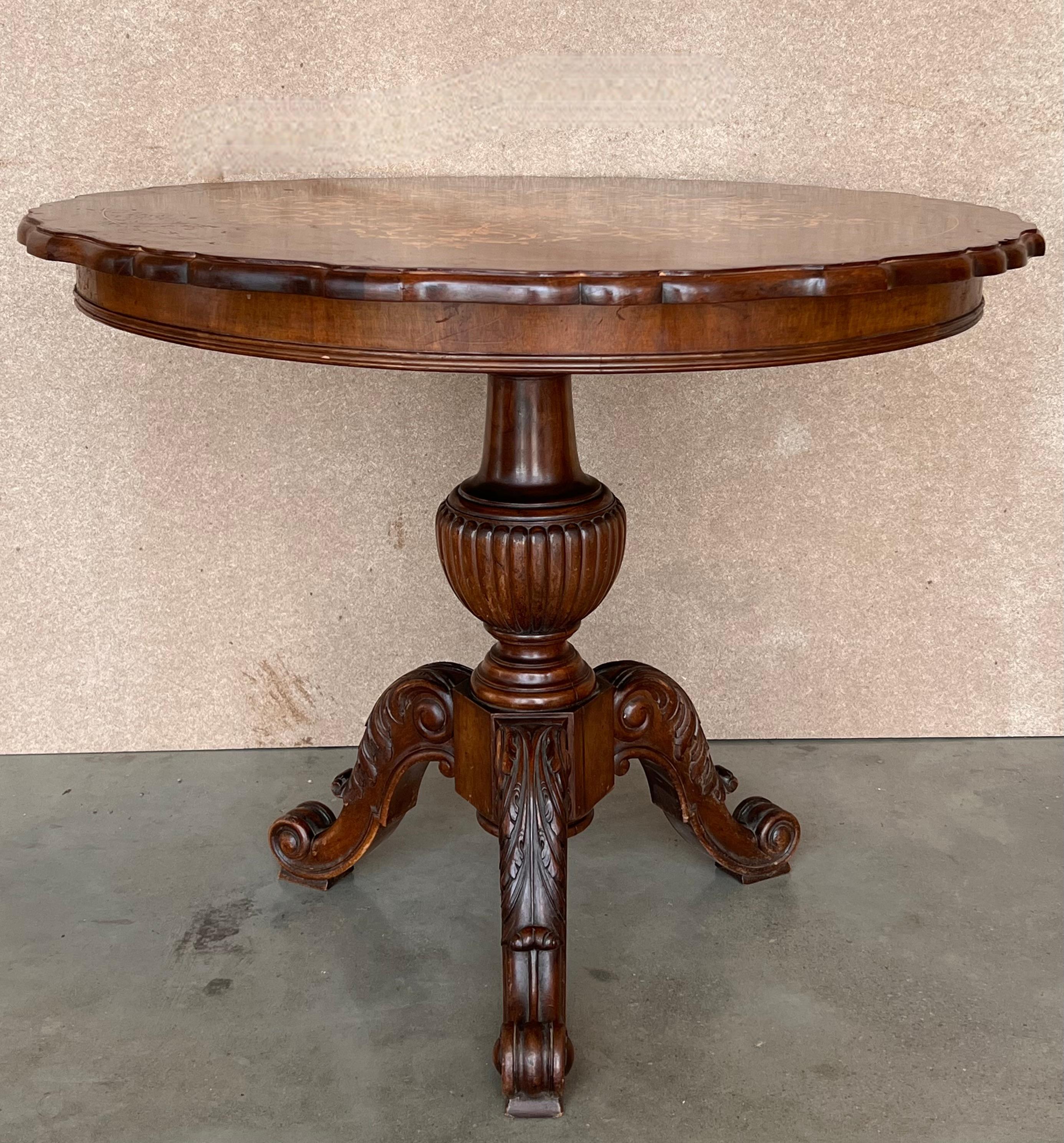 This Italian round pedestal wooden table from the mid to late 19th century features an exquisite floral and birds parquetry motif inlay on the top, surrounded by a sectional motif in the surround. The apron echoes the decorative fleur banding found