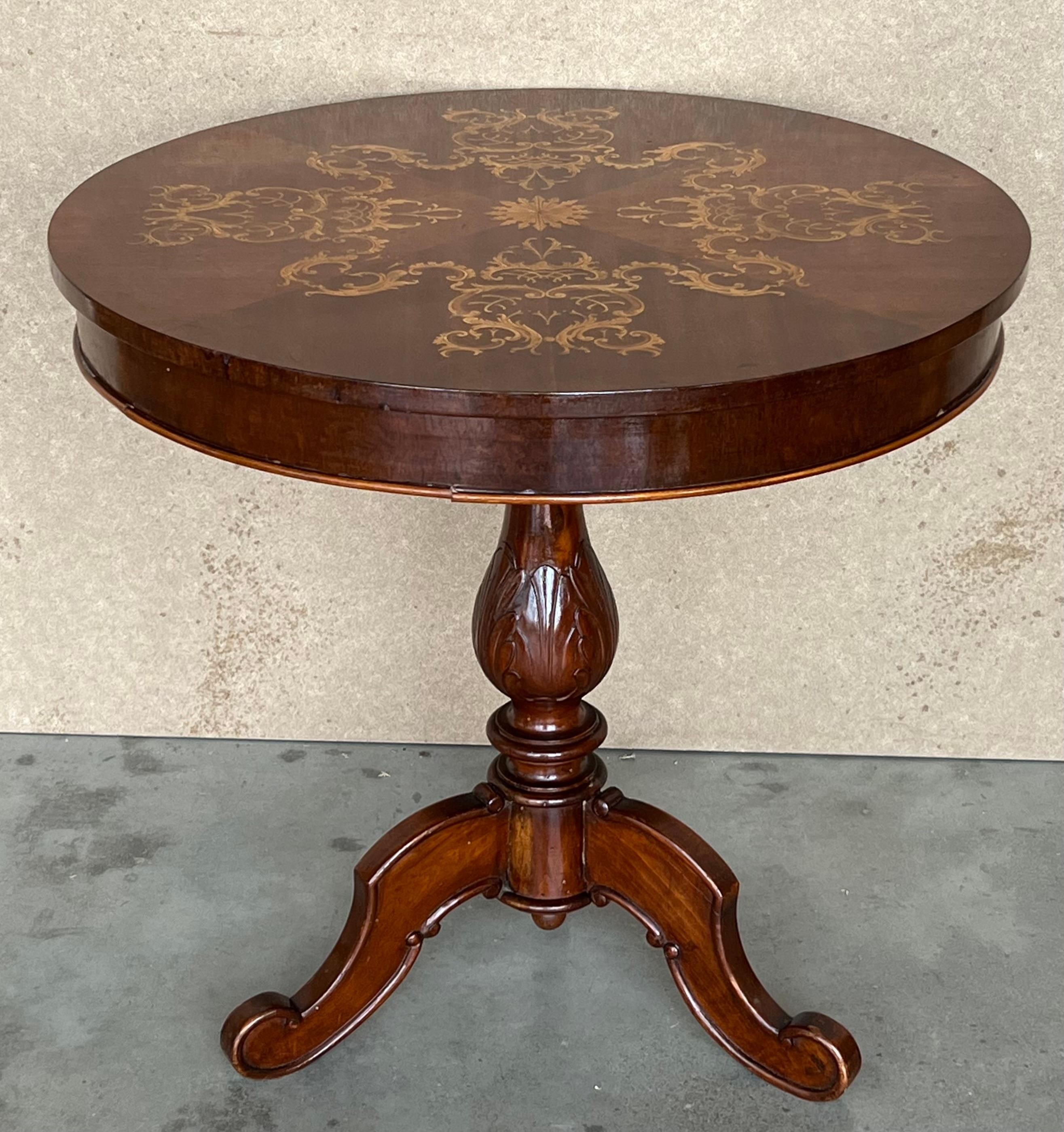 This Italian round pedestal wooden table from the mid to late 19th century features an exquisite floral marquetry motif inlay on the top, surrounded by a sectional motif in the surround. The apron echoes the decorative banding found on the edge of