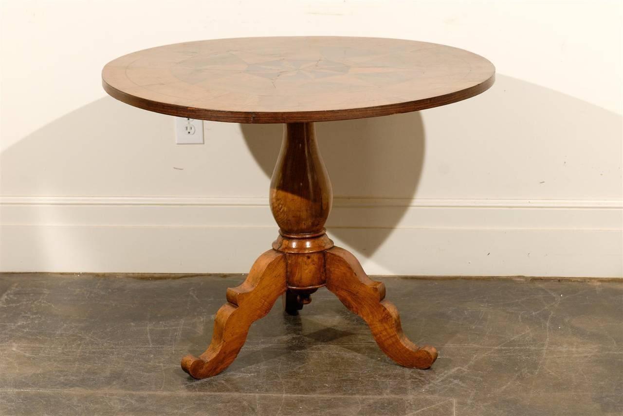 This Italian round pedestal wooden table from the mid to late 19th century features an exquisite star parquetry motif inlay on the top, surrounded by a sectional motif in the surround. The apron echoes the decorative banding found on the edge of the