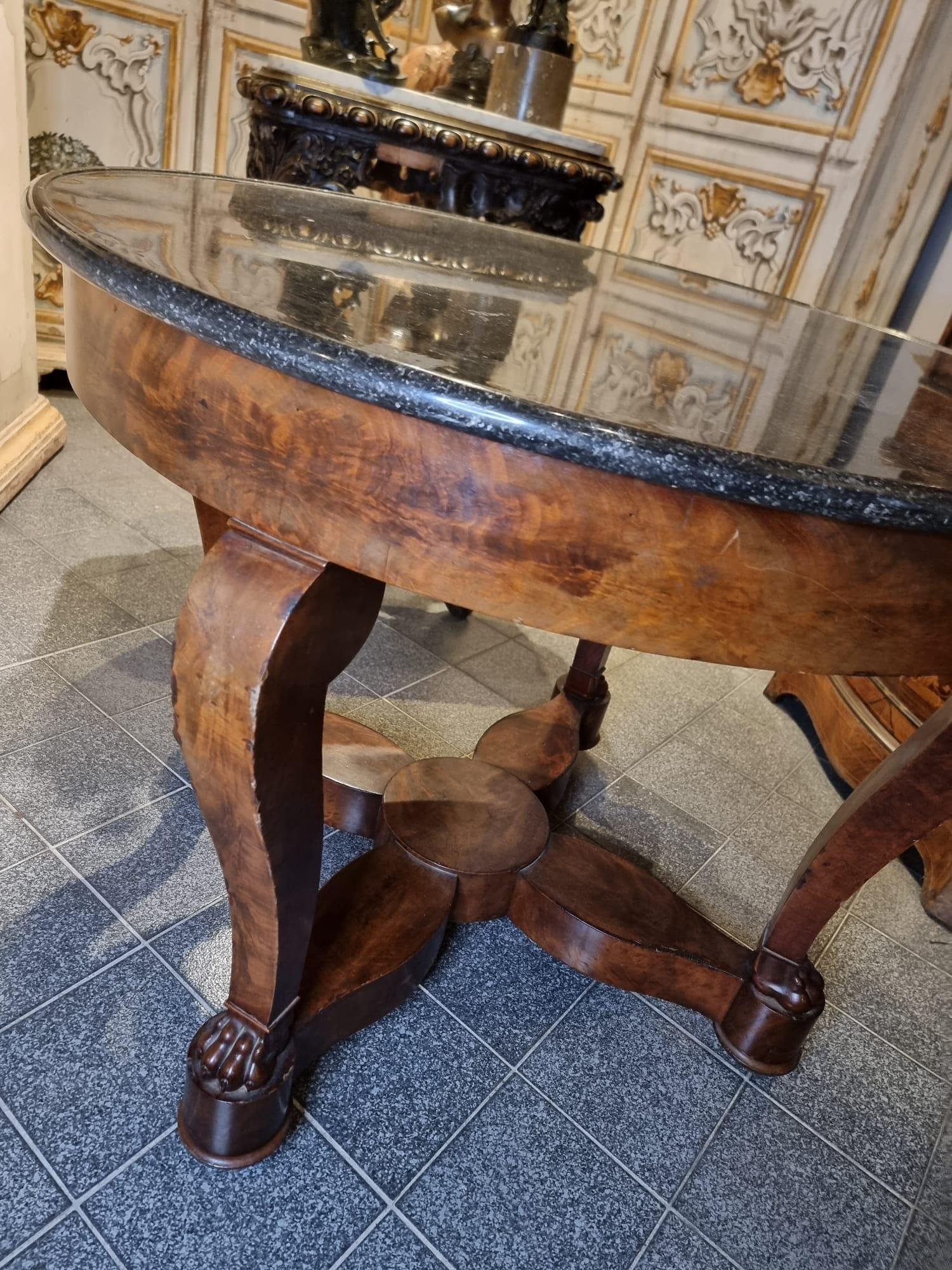 Important round table in mahogany wood and mahogany feather with four legs with feral paws resting on a cross and marble in shades of black, France, 19th century.

The table needs a restoration that will be done at our care and