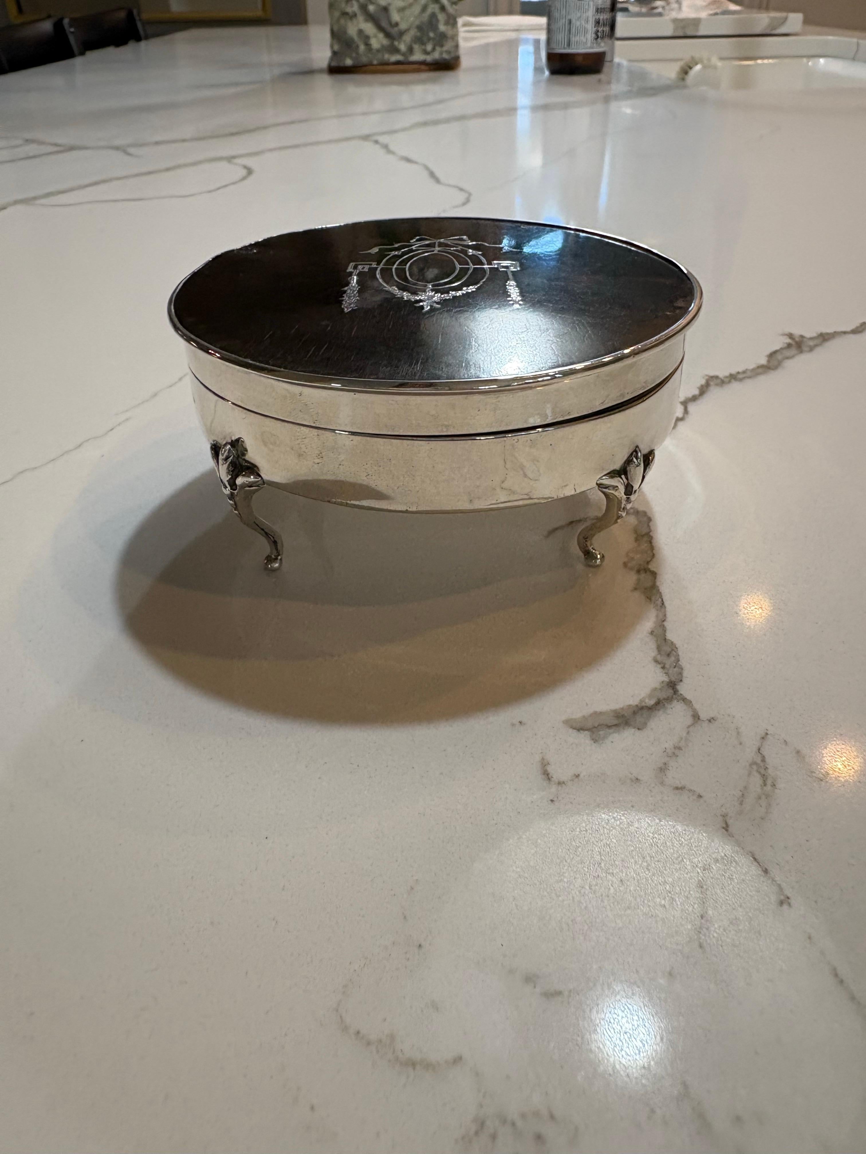 Scatola rotonda in guscio di tartaruga con bordi e piedini in argento stampato.  La parte superiore reca uno stemma a corona.  La parte superiore presenta anche una leggera scalfittura dovuta all'età.