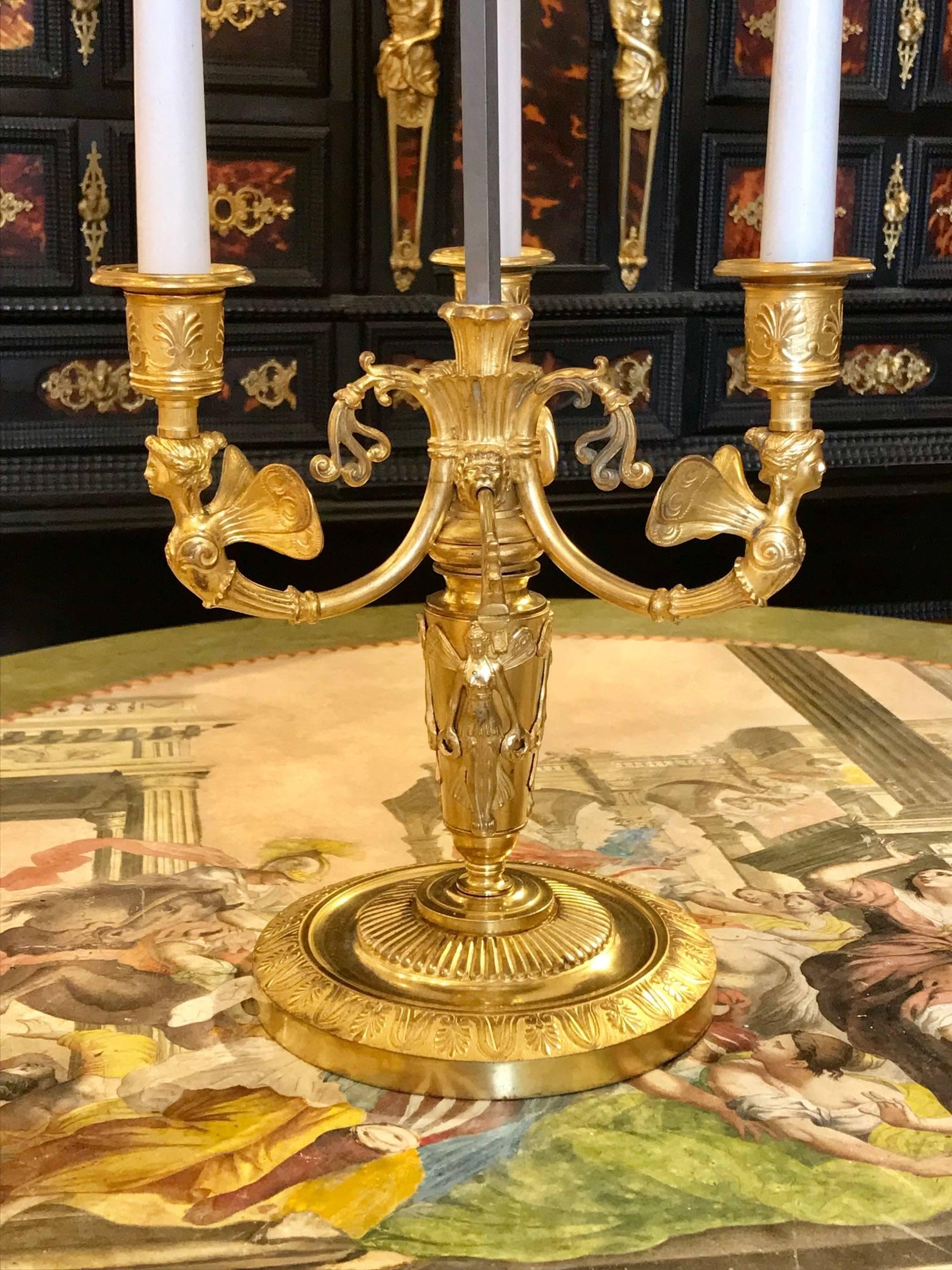Rare Russian Empire Ormolu Bouillotte lamp with original painted tole shade

Neoclassical winged female busts supporting three candles
Both the shade and candle supports are movable, each being controlled by an arrow
through a lion's