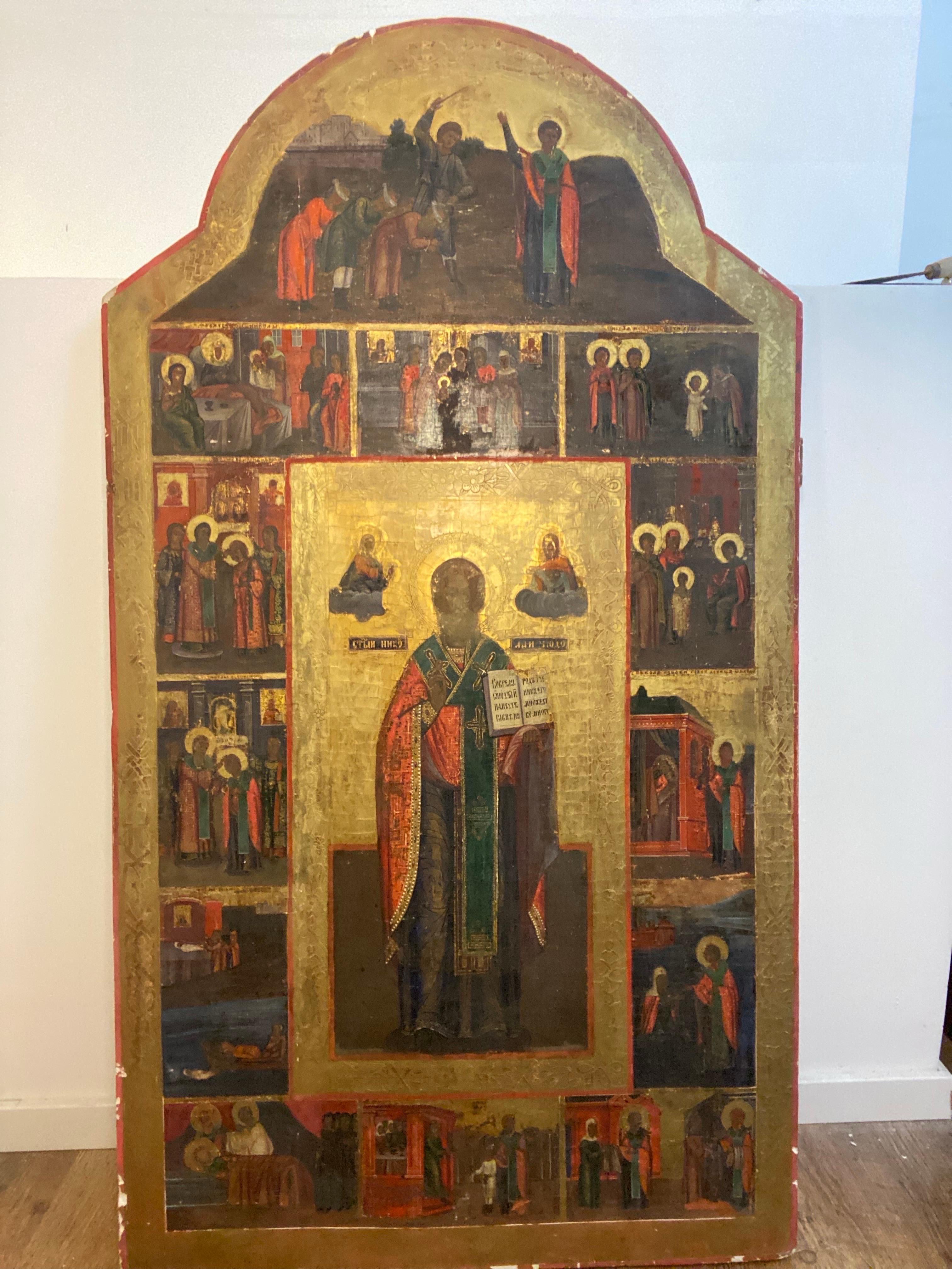 Hand made wood painting of a priest character with cape holding a book and 16 additional characters on the sides.