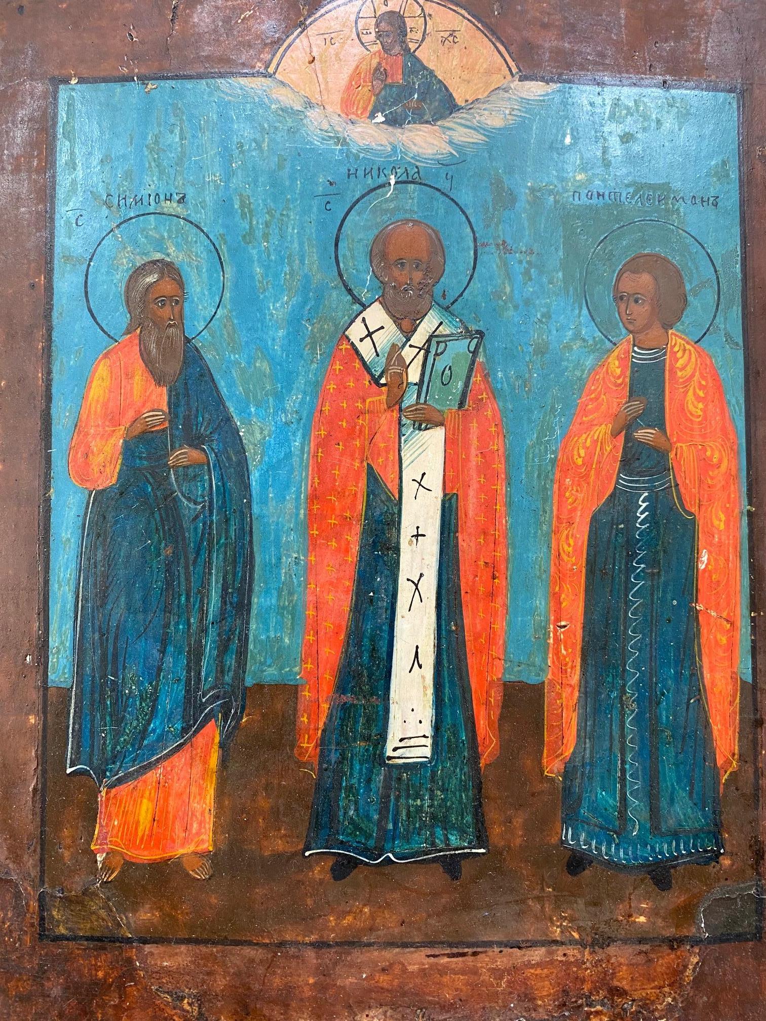 19th century Russian Icon of Saint Nicholas, likely first half 19th century, with I believe egg tempera on gessoed wooden panel, depicting Christ in a hemi-circle reserve in the clouds at top of panel, looking down and blessing Saints Simeon,