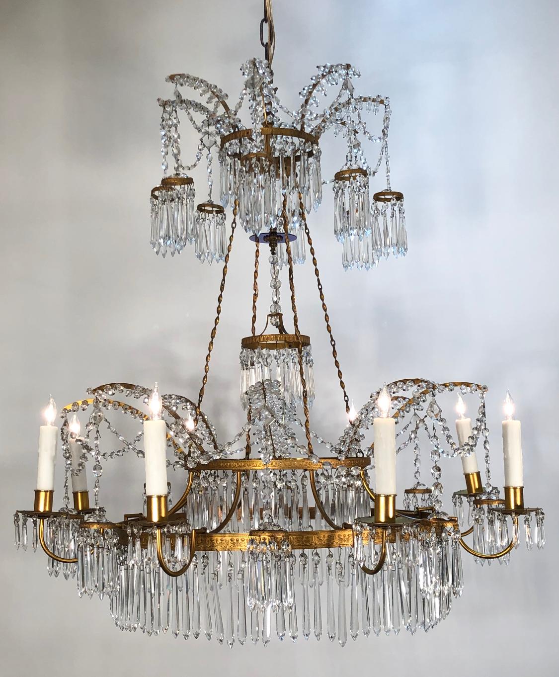 This French made elegant Russian/Baltic Empire style chandelier is doré bronze and crystal with a cobalt crystal mounted hanging center pendant having a doré bronze repousse ring hanging below. The neoclassical frame has eight lights with bronze and