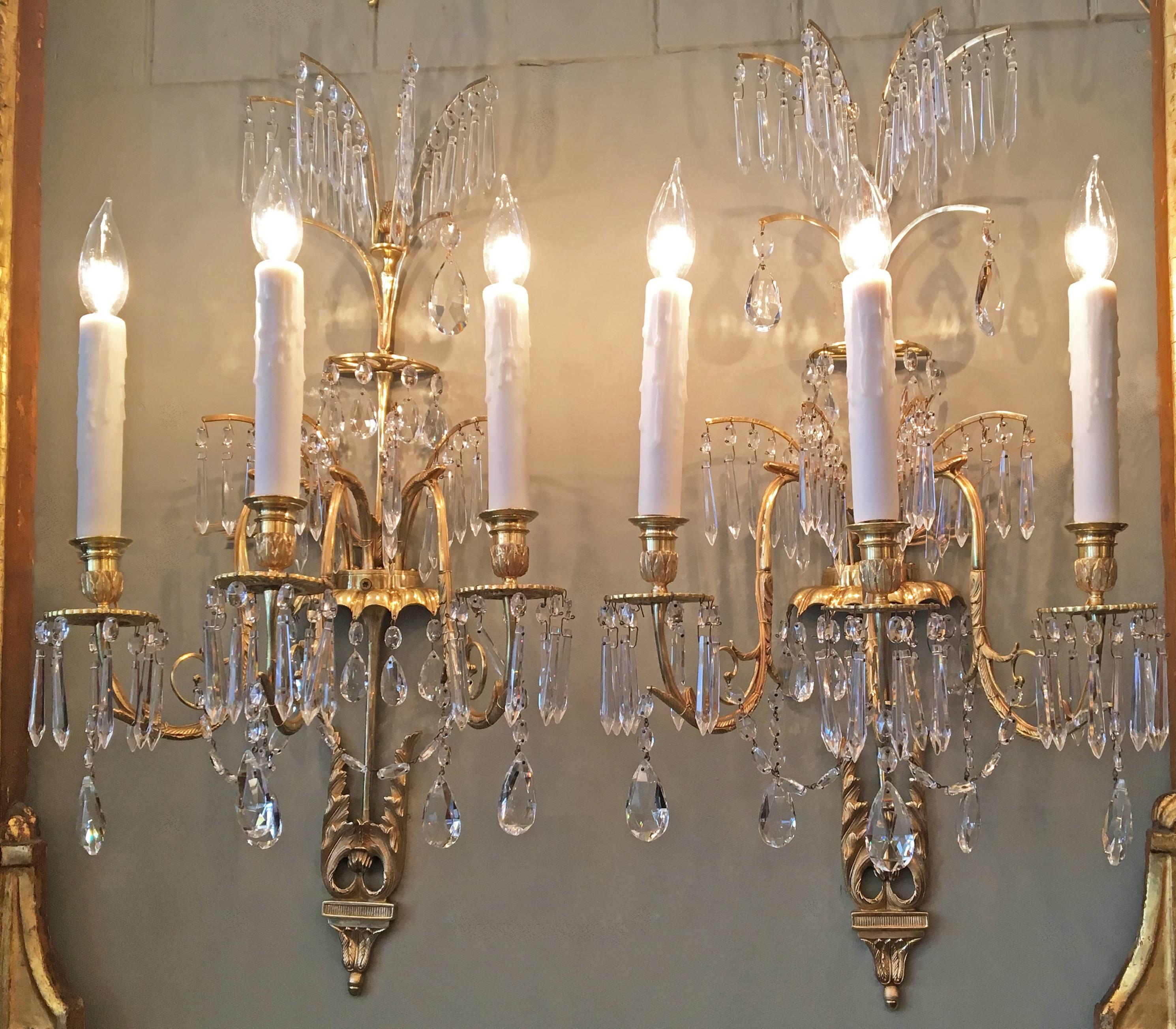 These elegant Russian/Baltic sconces are doré bronze and crystal with three lights. These Neoclassical sconces have Chinoiserie design. 

The frame has six bronze and crystal feathers above bronze filigree half-ring with crystal prisms followed by