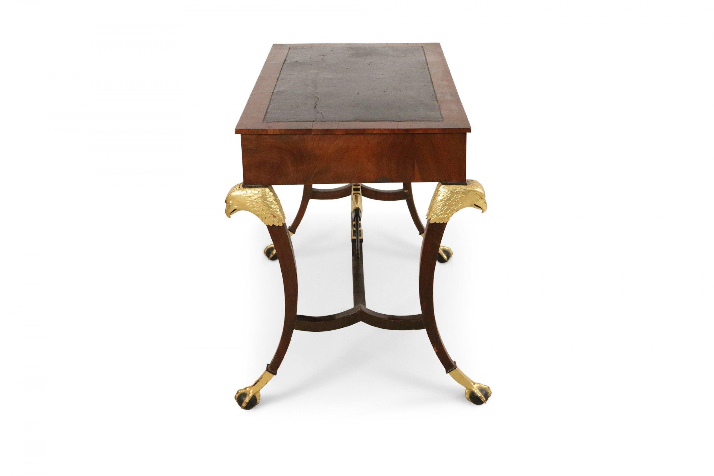 Russian (19th Century) mahogany desk with inset black leather top, key-locked drawer & pull out writing tray with a stretcher having a centered black & gilt eagle connecting 4 saber legs with gilt eagle heads and talon claw & ball feet.