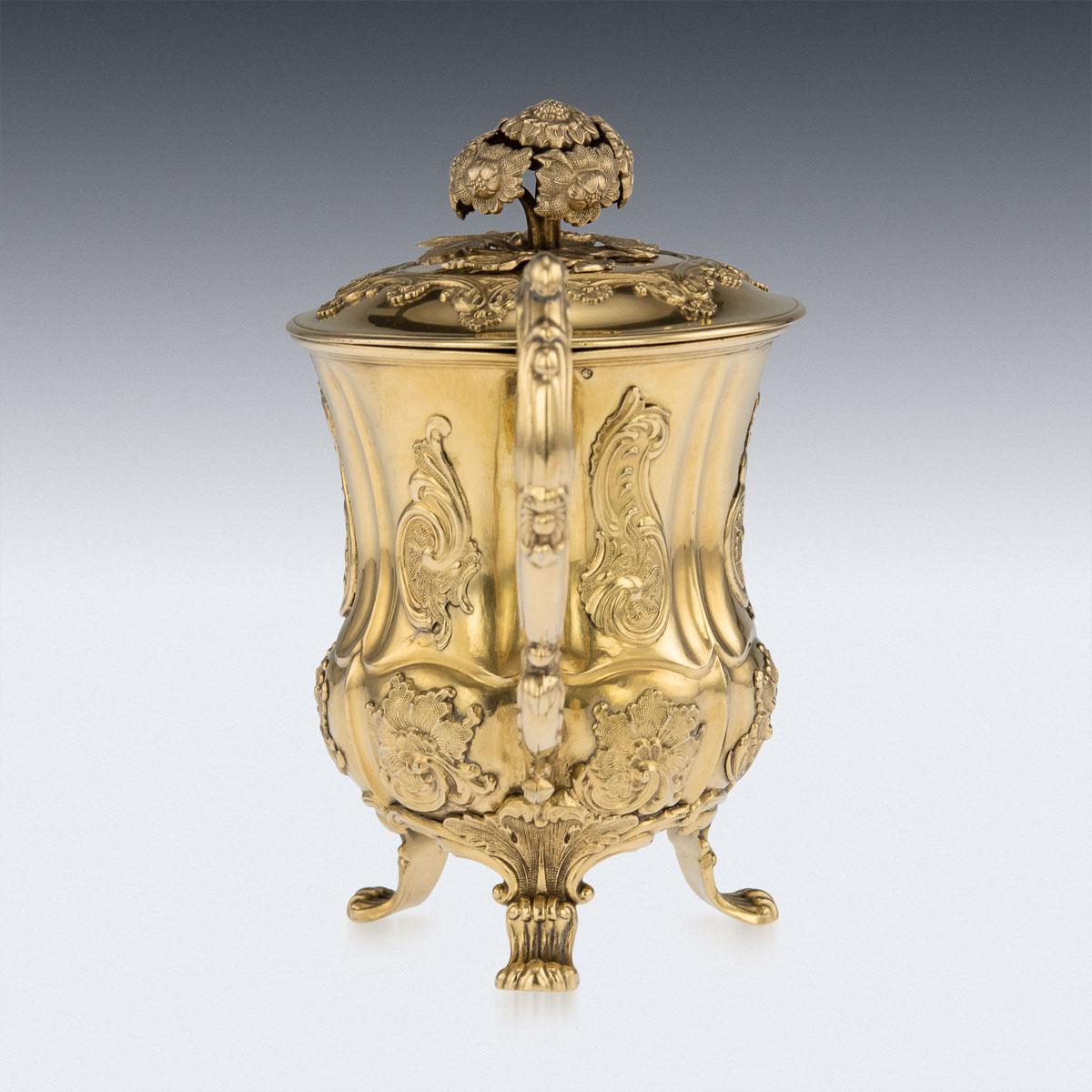 Antique mid-19th century Russian solid silver-gilt cup with cover, of fluted baluster form, the body and lid applied with clusters of scrolls and foliage, standing on 4 scroll feet and applied with a decorative handle, the lid set with a knop formed