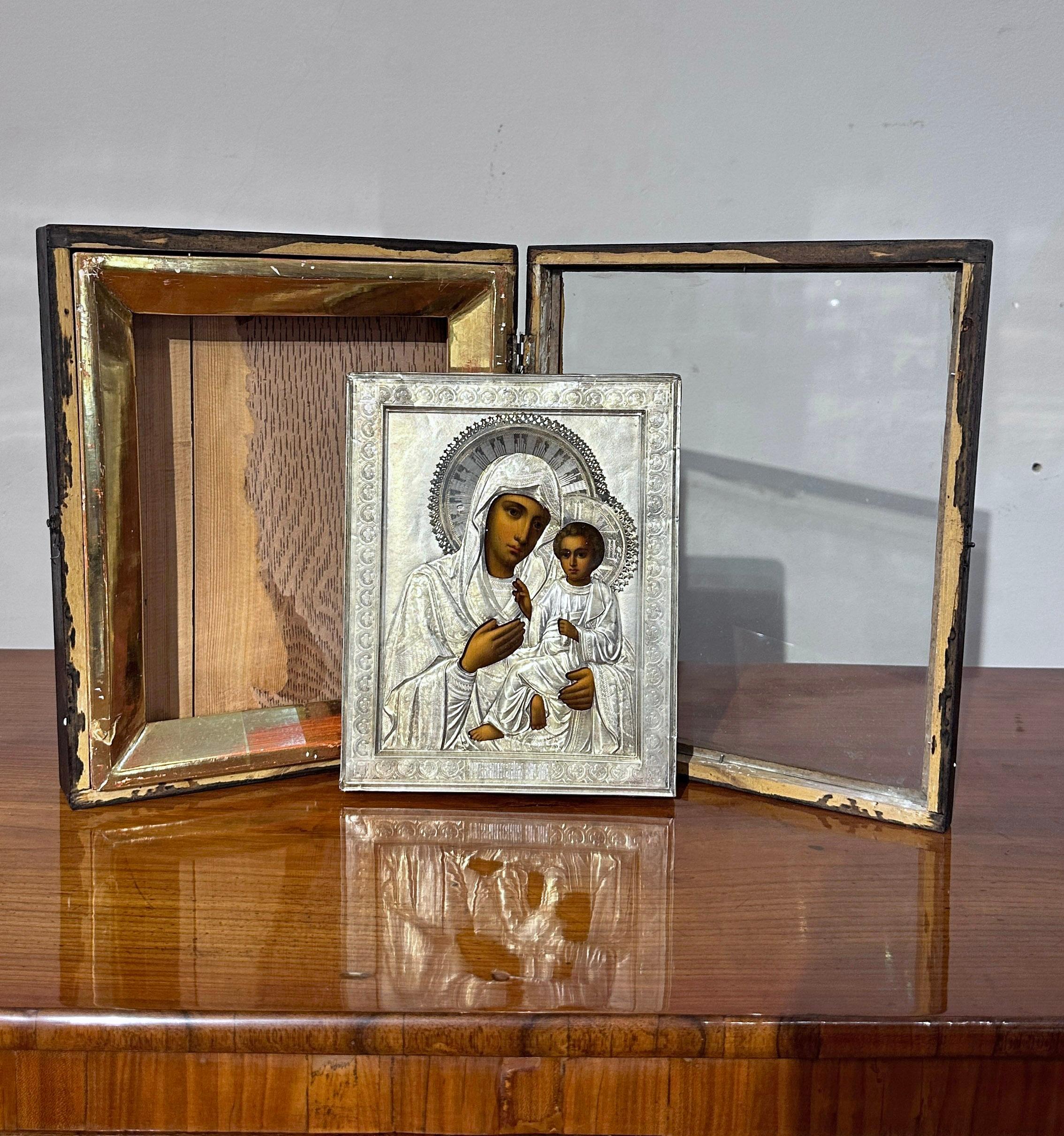 Beautiful Russian travel icon painted in oil on wooden tablet, with a refined silver lancet. The Madonna and child are represented with great skill, following the traditional style of Orthodox icons. Their clothes and background are made of finely