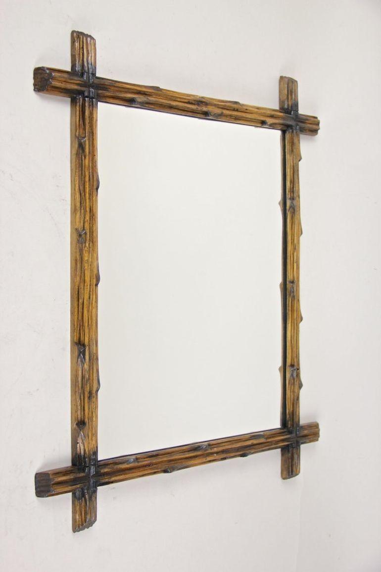 Extraordinary rustic, late 19th century Black Forest wall mirror out of Austria. Artfully handcarved around 1890, this unusal stained Black Forest wall mirror impresses with a simple but elegant design, crafted out of basswood, showing the famous