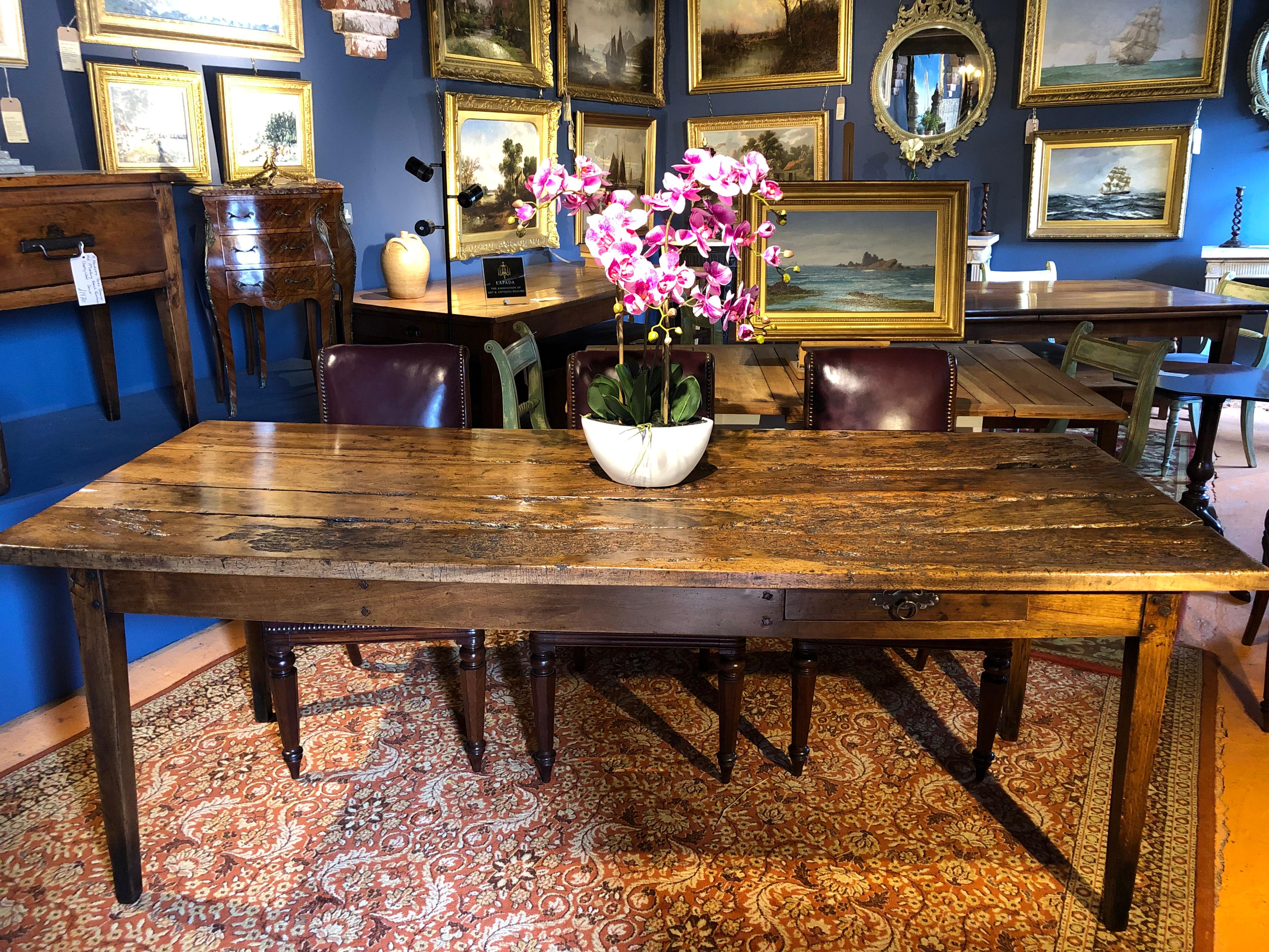 An incredibly rustic early 19th century French fruitwood (probably apple) farmhouse table. The top, naturally worn over the last 170 years this table has been reconstructed, sealed and re-polished by one of the top conservators of furniture in the