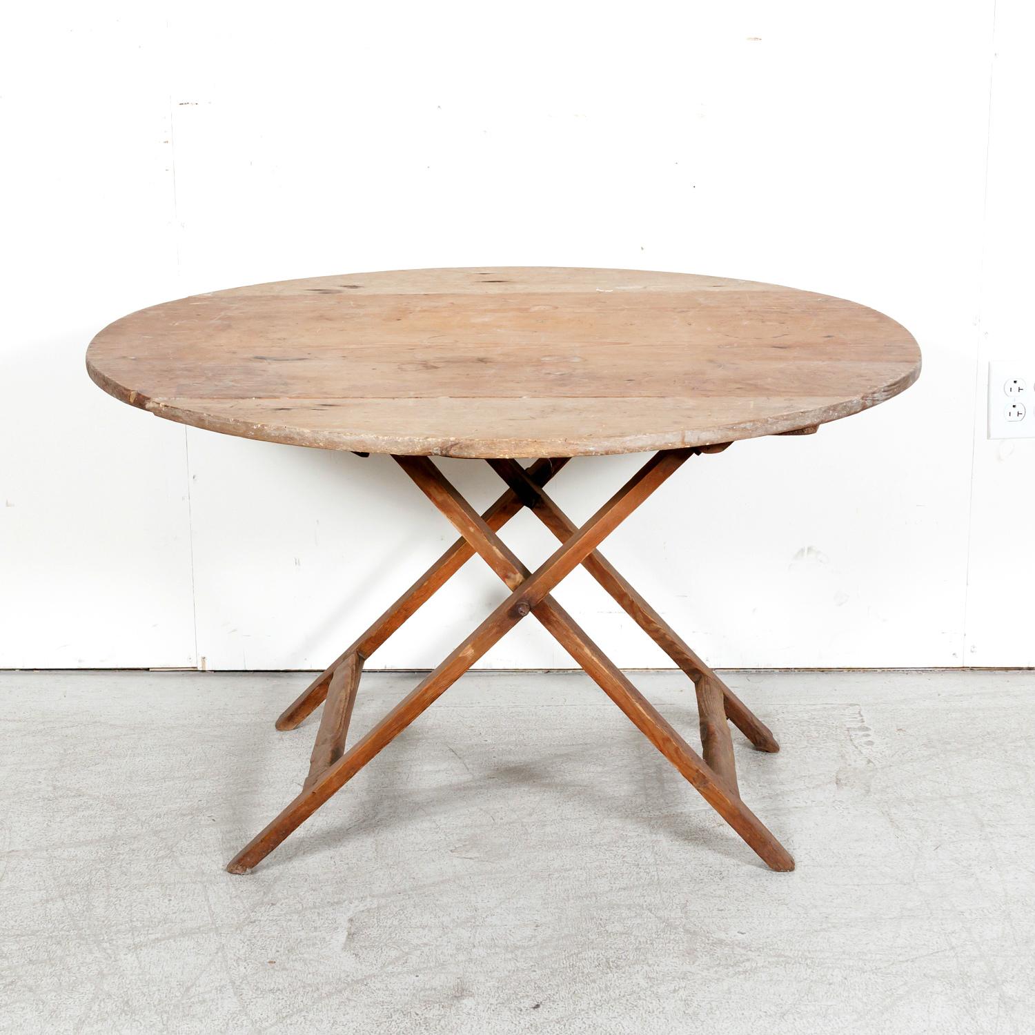 A 19th century rustic French campaign or coach table handcrafted of pine in the South of France, circa 1890s. Having a slightly oval plank top with a beautiful sun bleached patina from over a century of use under the hot Provençal sun. Raised on a