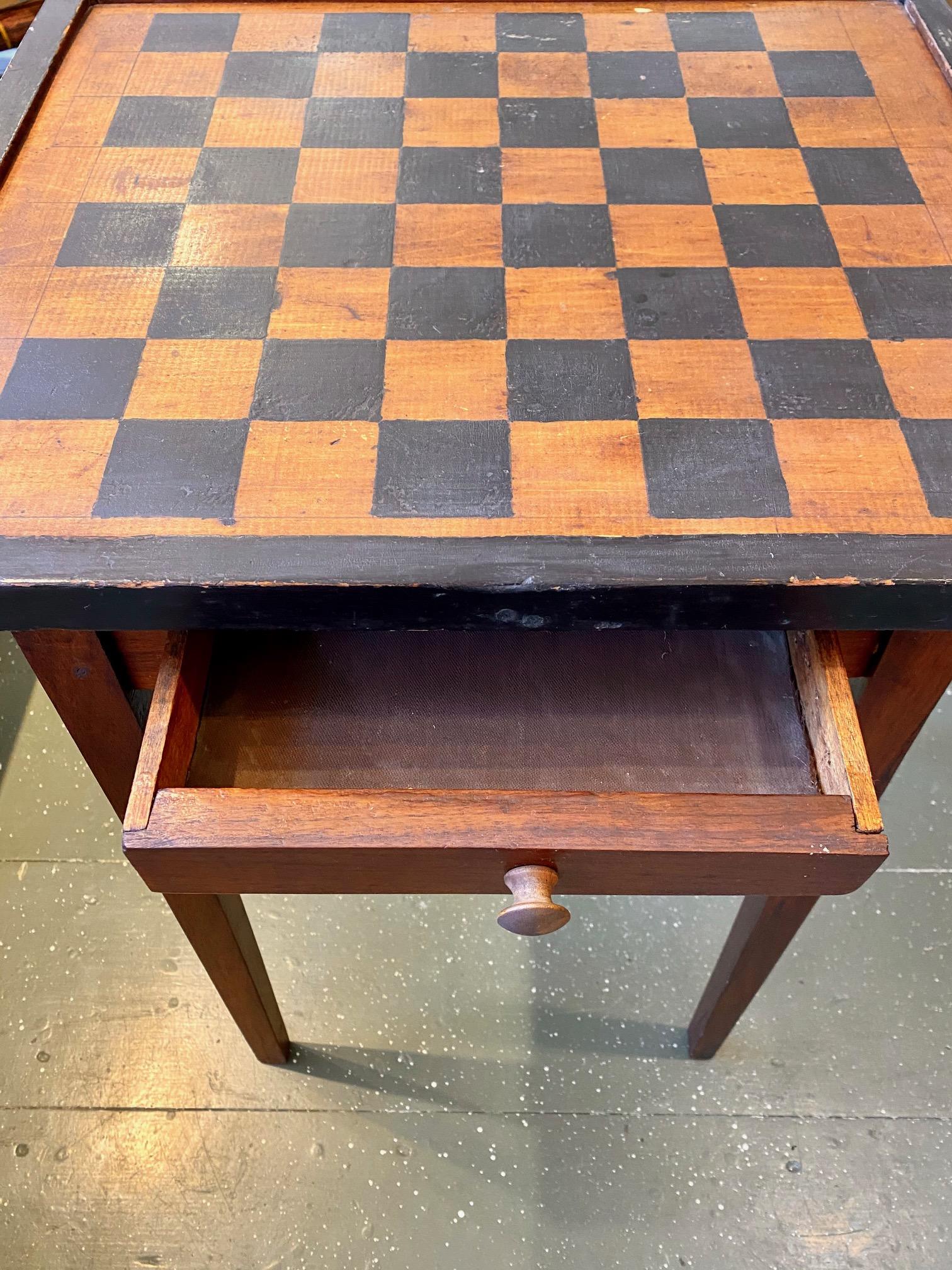 Mid to Late 19th Century rustic painted game table, a country Hepplewhite style game stand with painted checkerboard top enclosed within shallow raised gallery, above opposing narrow drawers, raised on tapering square legs. The unique opposing