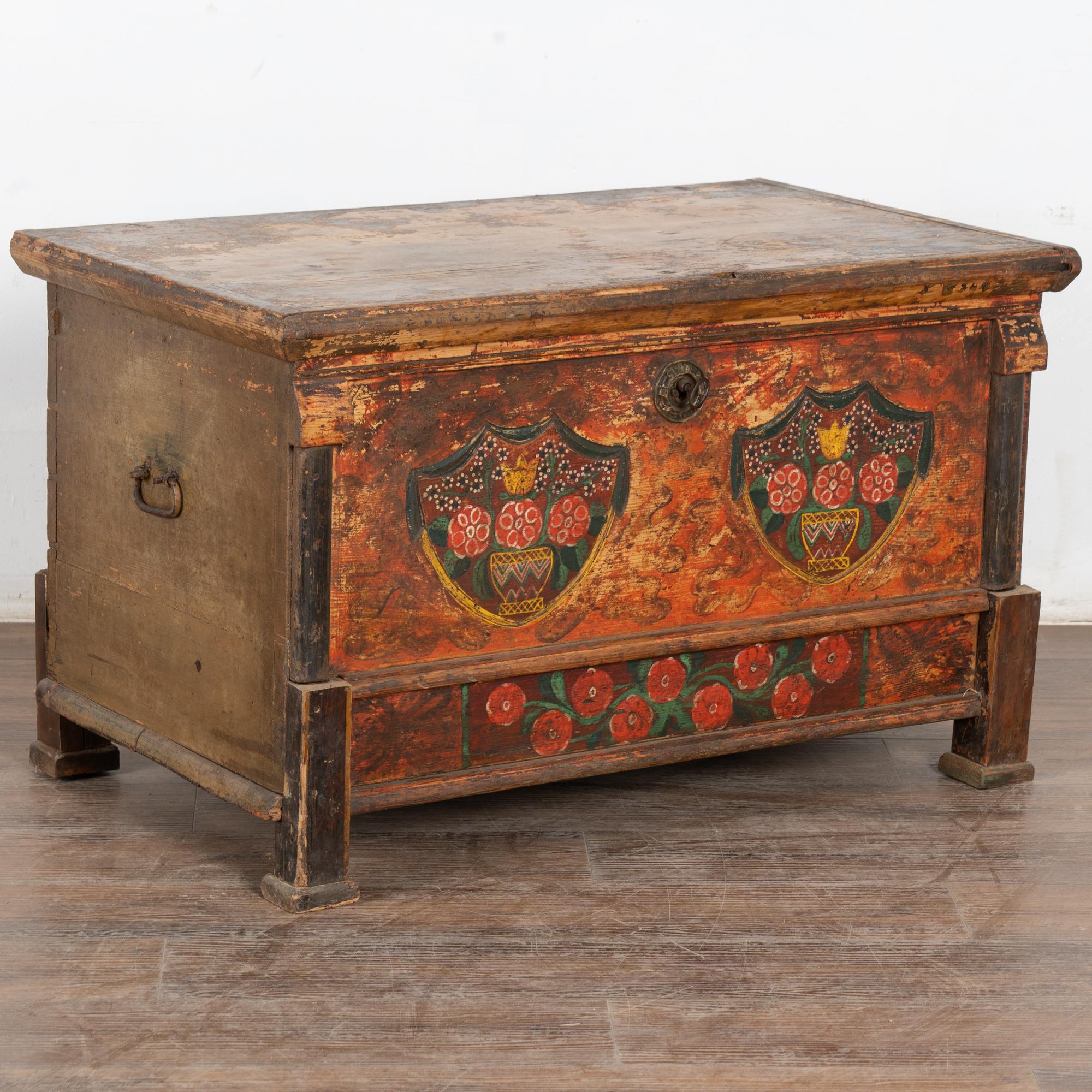 La peinture colorée est entièrement d'origine sur cette magnifique malle à toit plat. Les fleurs étaient un ornement traditionnel, comme on peut le voir sur le devant de cette malle fabriquée à la main, avec des détails floraux rouges, orange, verts