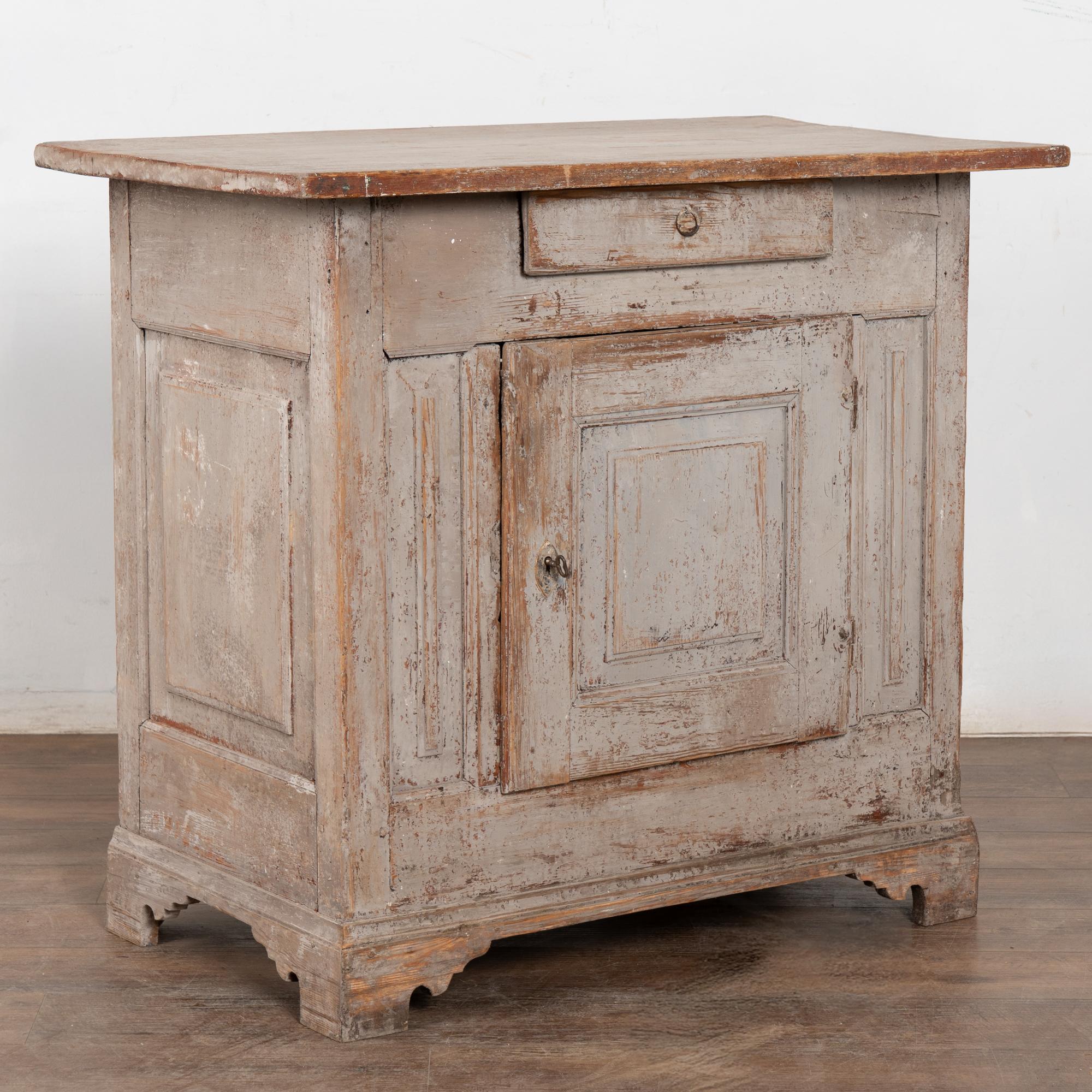 Ancienne armoire ou petit buffet en pin suédois avec un seul tiroir.
La finition peinte grise d'origine a été altérée par des générations d'utilisation, révélant la patine chaude et vieillie du pin en dessous.
Restauré, solide et stable, une clé