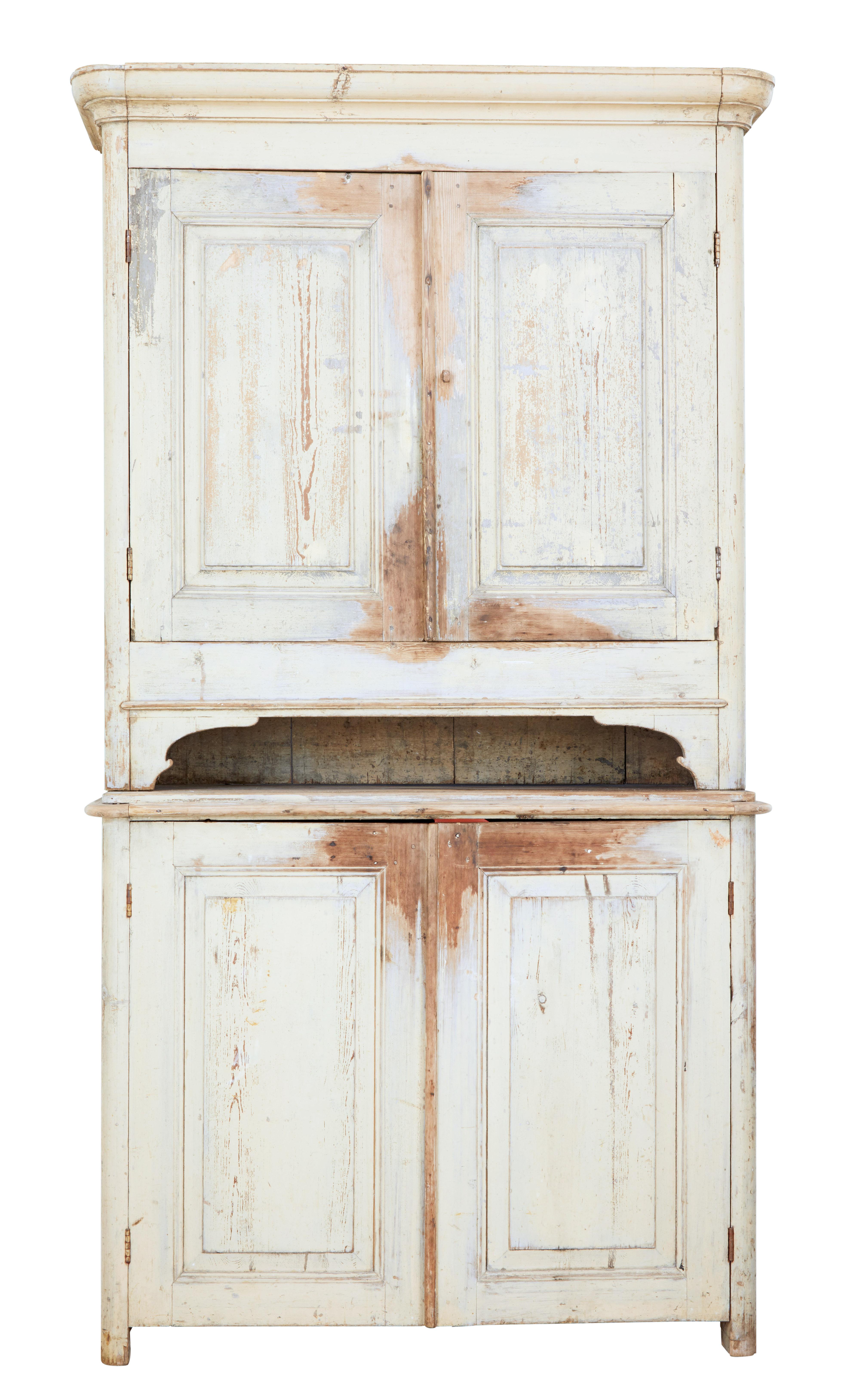Rustic piece of Swedish pine furniture, circa 1860.

2 part kitchen cupboard still in its original paint. Top section with shaped cornice and double door cupboard containing 2 fixed shelves. Further storage for jars below the top cupboard. Bottom