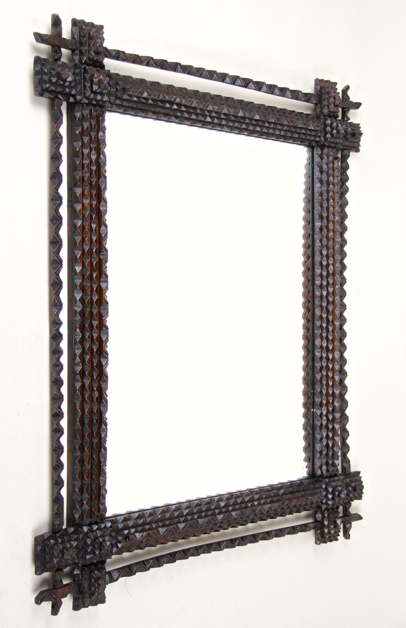 Miroir rustique de Tramp Art de la fin du 19e siècle en Autriche. Sculpté à la main dans du tilleul vers 1870, ce miroir mural rural présente une surface teintée brun foncé en excellent état d'origine. Le point fort de ce miroir ancien est sans
