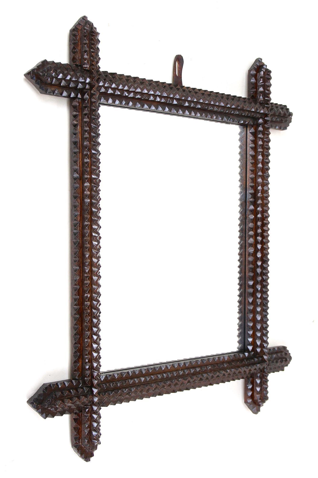 Extraordinary rustic Tramp Art wall mirror from the period around 1880 in Austria. This unique hand carved wooden mirror has been artfully crafted in the late 19th century out of basswood and shows a lovely dark brown surface finished with a