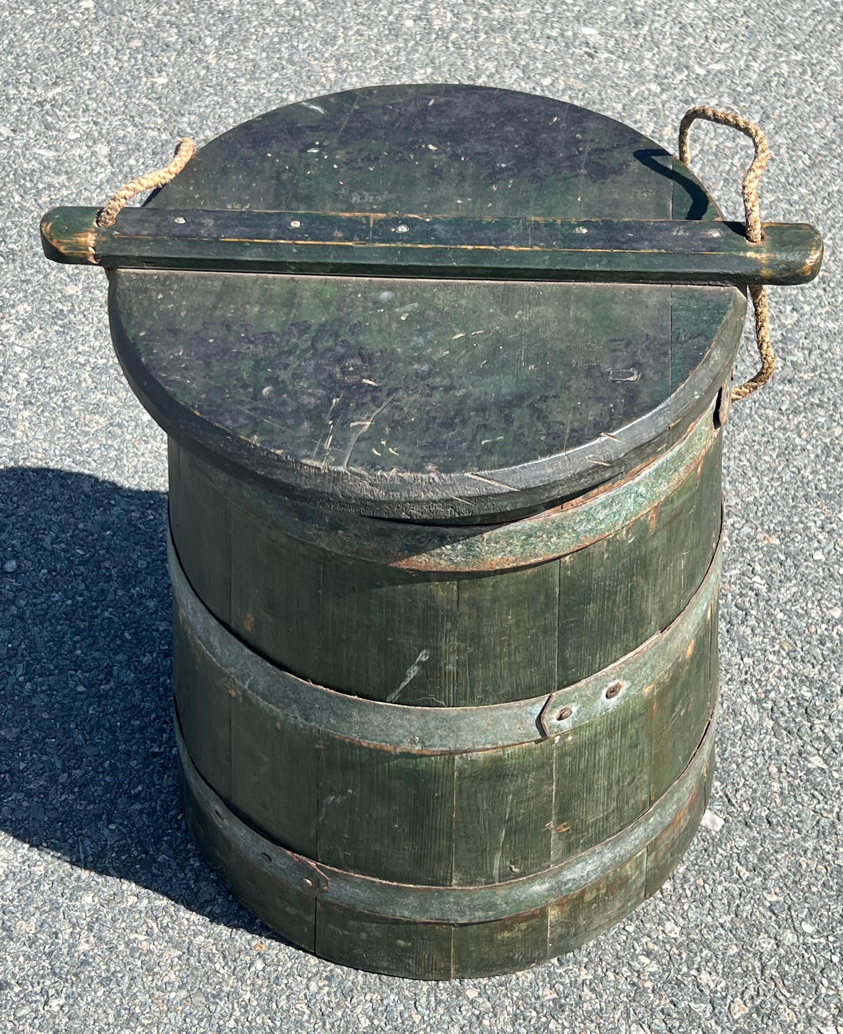 19th Century Wooden Bucket in original green paint, likely crafted by a cooper using slatted construction and metal banding, slide top with rope handle for covering items and transporting.