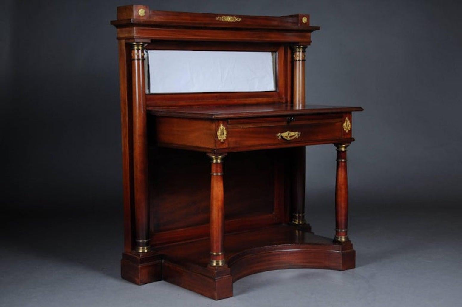 Legno massiccio, impiallacciatura in mogano. Piastra di copertura rettangolare su una cornice poco appariscente. La base è ad arco. Applicazioni in bronzo finemente cesellate e dorate. Piano di lavoro / tavolo da scrittura rimovibile sotto la