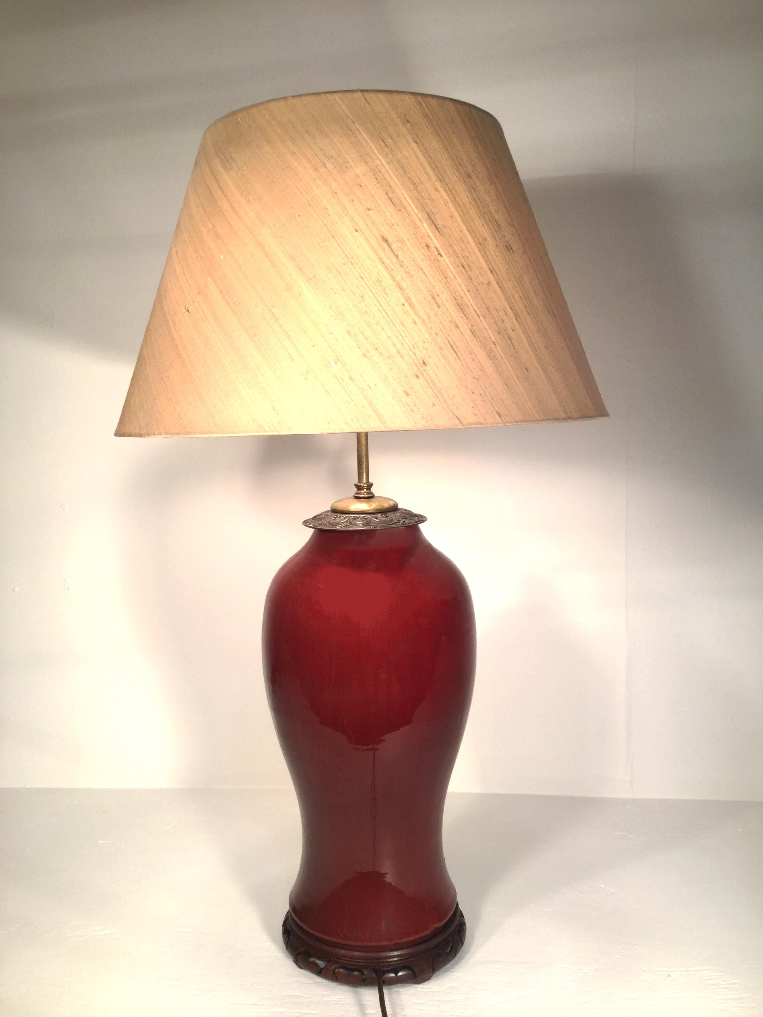 This beautiful 19th century Sang De Boeuf urn was mounted and transformed into a lamp during the early 20th century. The grand scale and oxblood color of this table lamp make it wonderful for any room. It is mounted on a teek carved base with bronze