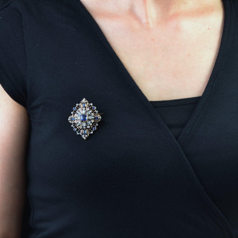 Antique jewelry in 18 karat yellow gold, and silver.
Of shuttle shape, it is decorated in the center of a cushion- cut blue sapphire surrounded in radiation of antique- cut diamonds, the top and the bottom are a pattern in flower of lily, set of