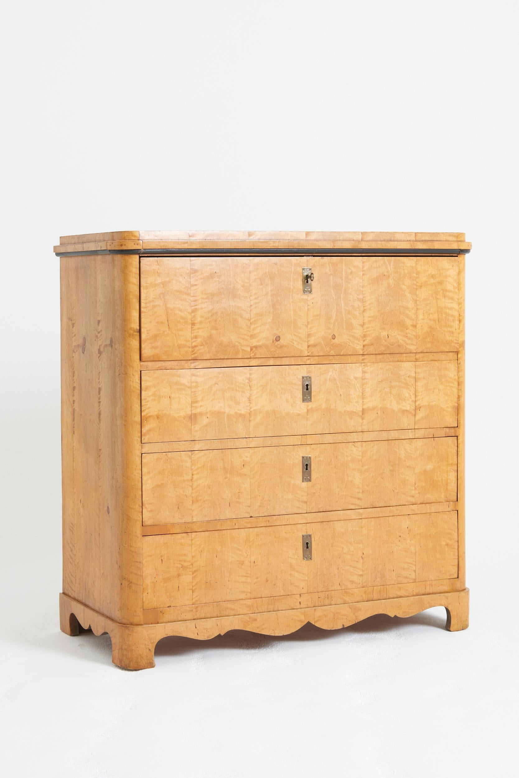 A satin birch chest of drawers, the top drawer revealing a fitted secretaire.
Sweden, mid 19th Century
