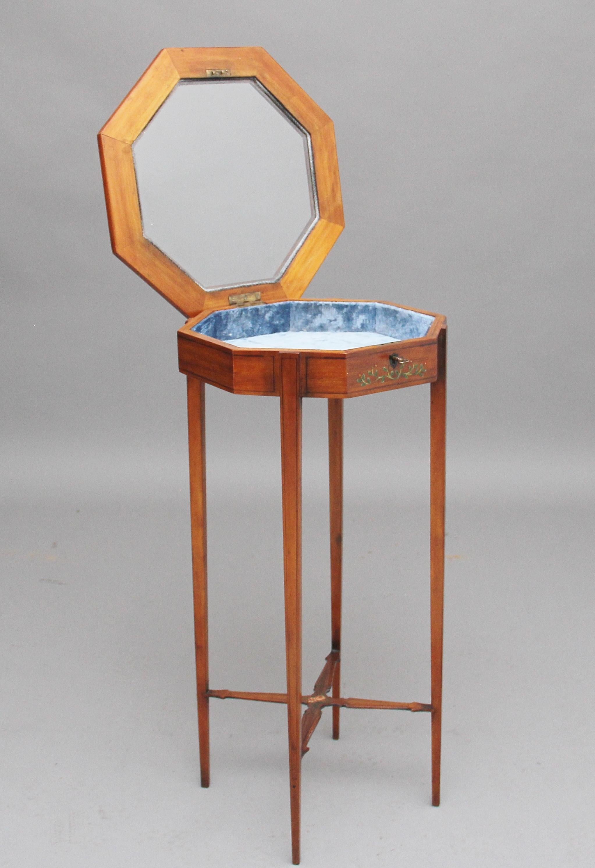 19th century satinwood and painted bijouterie table, with a hinged lift up octagonal glazed top opening to reveal a blue velvet lining, the frame of the top having painted floral decoration, the frieze below also painted, the top can also be locked,