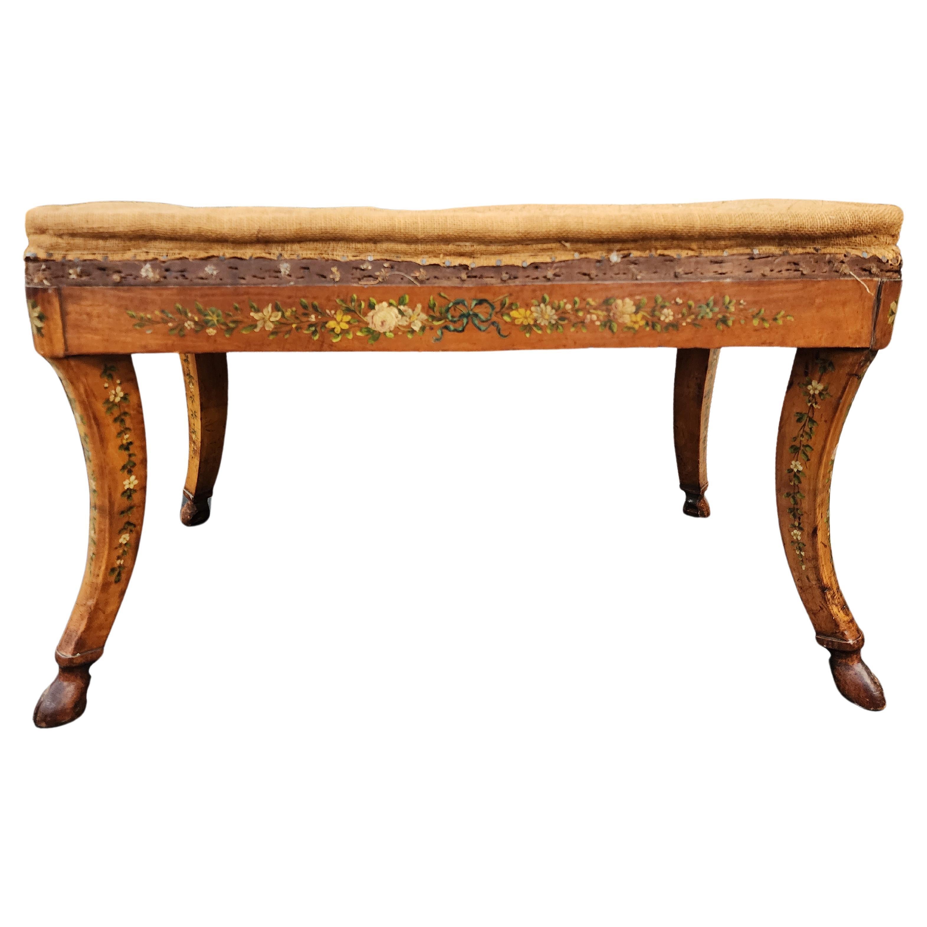 Mauve period, Ceylon satinwood bench with saber legs, carved hoofed feet and delicately painted floral accents. This Gilded age satinwood bench from the late 19th century exudes an elegance that reflects the tastes of the era. The harmonious blend