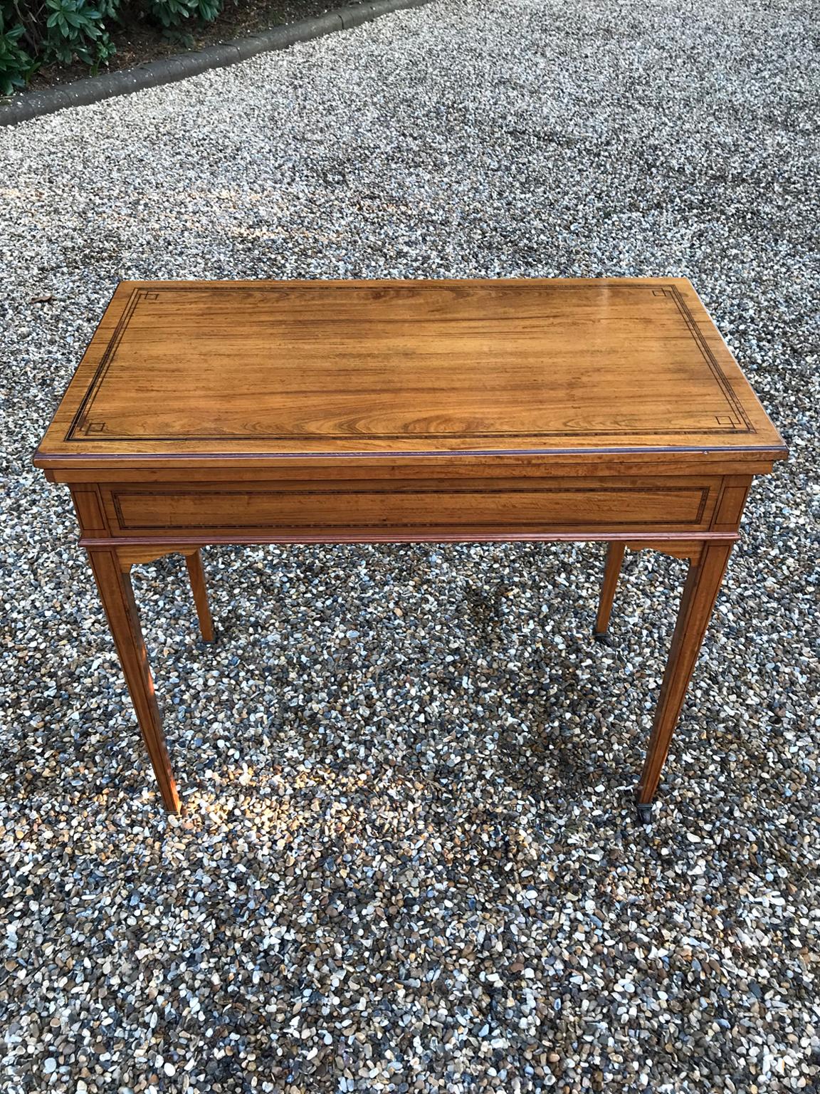 19th century Satinwood card table, with rosewood crossbanded and ebony strung folding. There are useful compartments on the inside when swivelled before opening up the card table. On square tapering legs and original brass castors.

circa