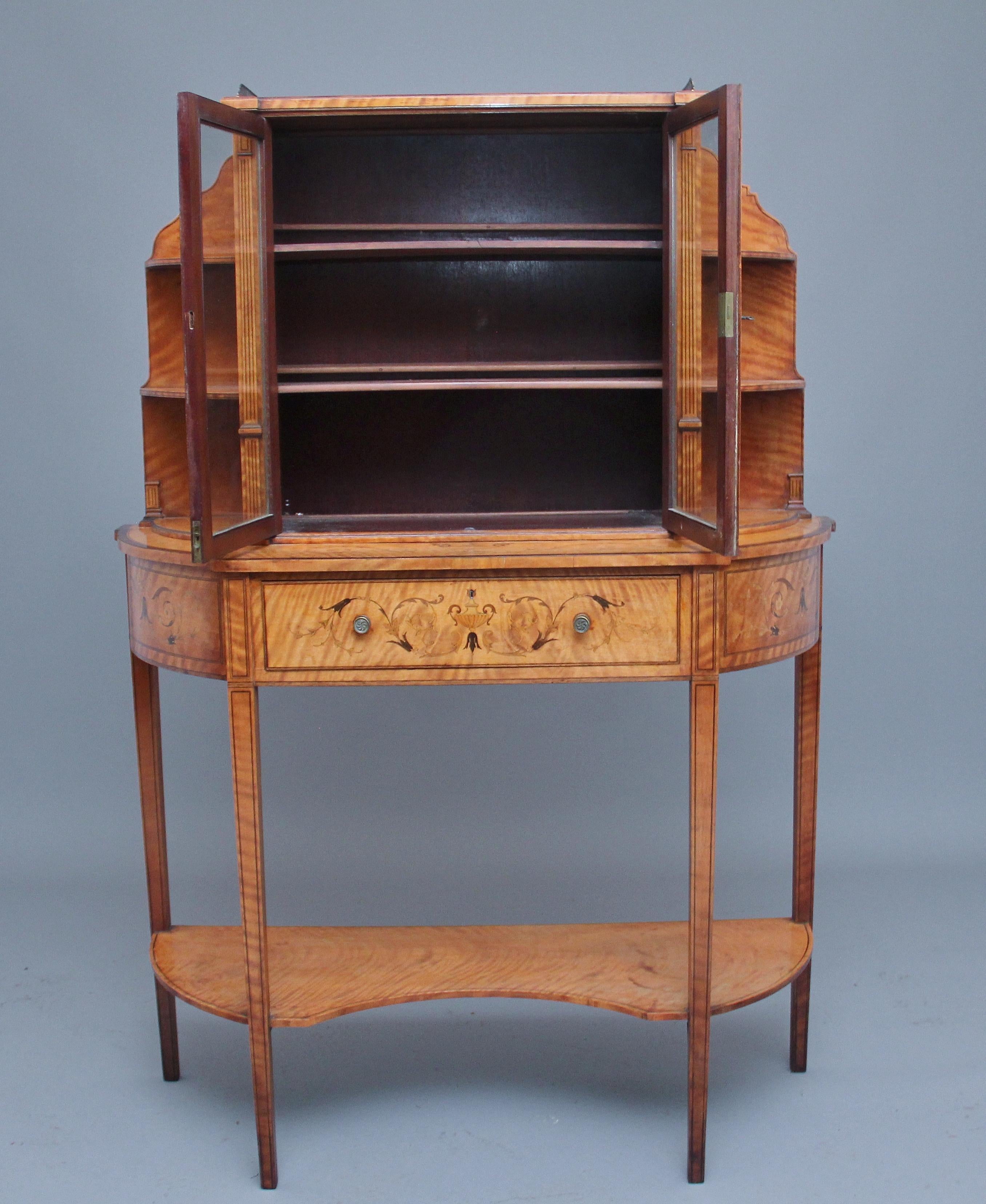 19th century satinwood display cabinet in the Sheraton style, having a pierced brass gallery above two glazed doors, opening to reveal two shelves inside, flaked either side by graduated shelves and reeded pilaster decoration, the base section