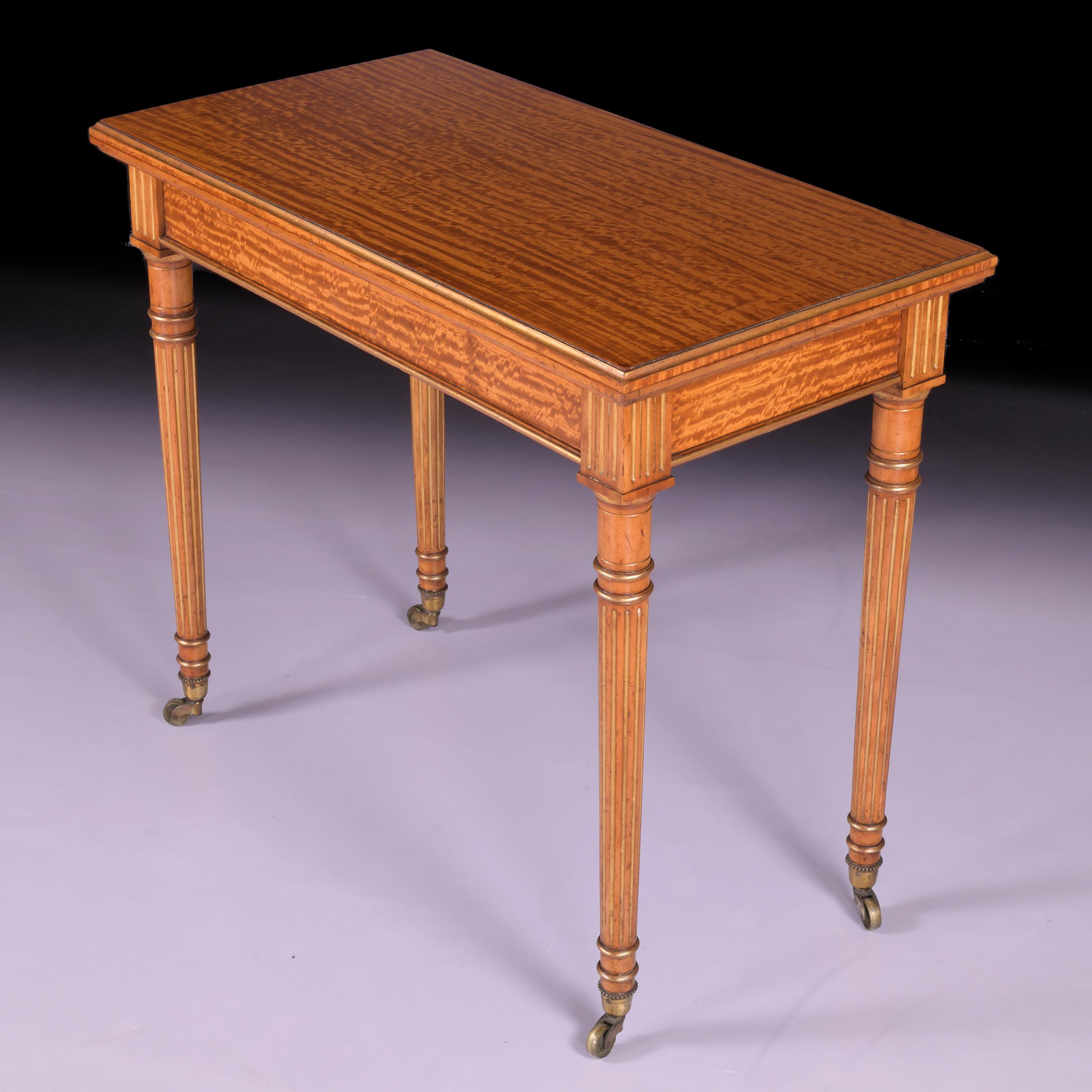A superb 19th century satinwood and parcel gilt games table, the rectangular fold-over top with a gilt moulded edge, opening on telescope action to a purple baize playing surface, above a plain frieze, raised on fluted taped legs ending in brass