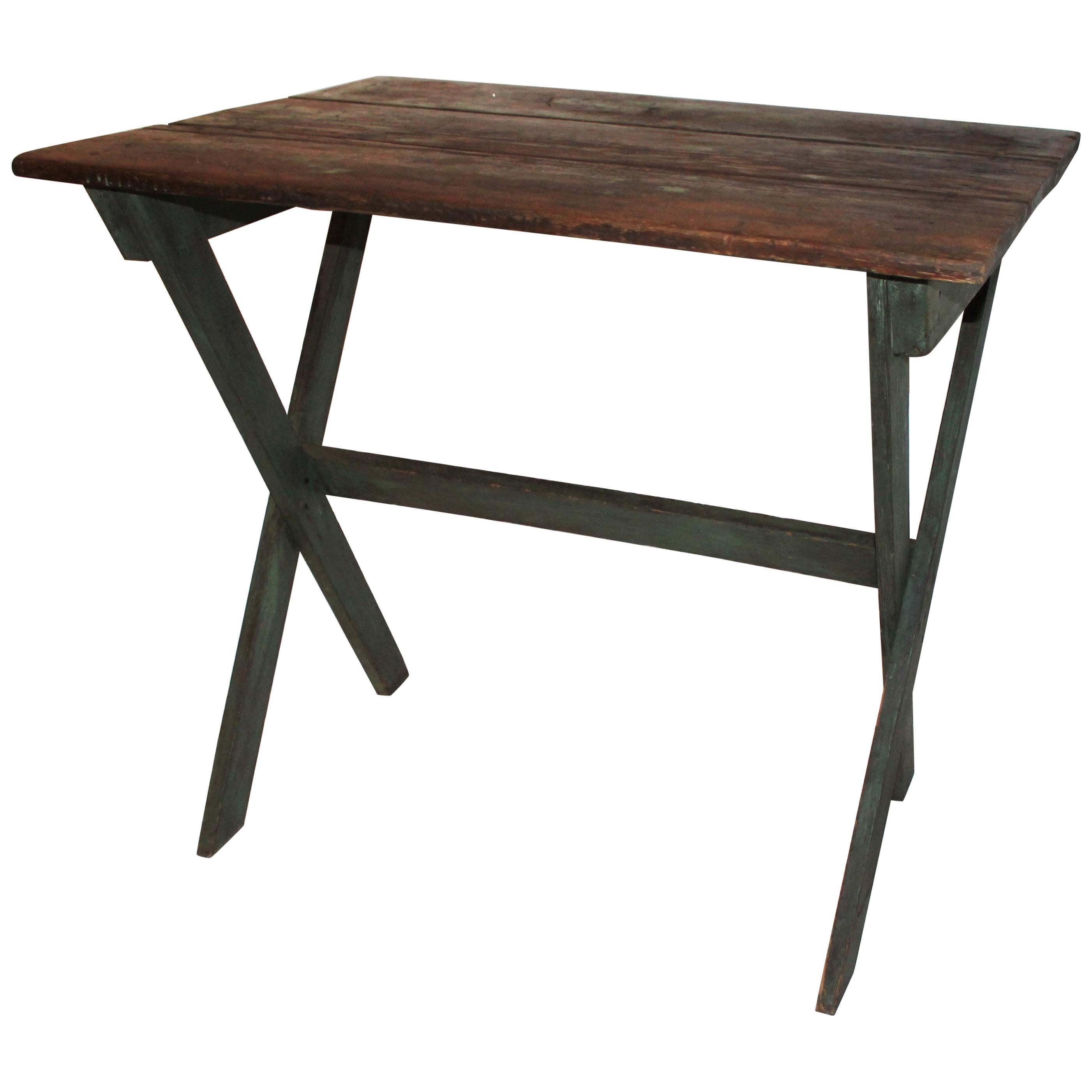 19th century original apple green painted sawbuck table. This rustic three board top table is all square nail construction. It was probably used as a work table on the farm or kitchen. It is in great sturdy condition.
