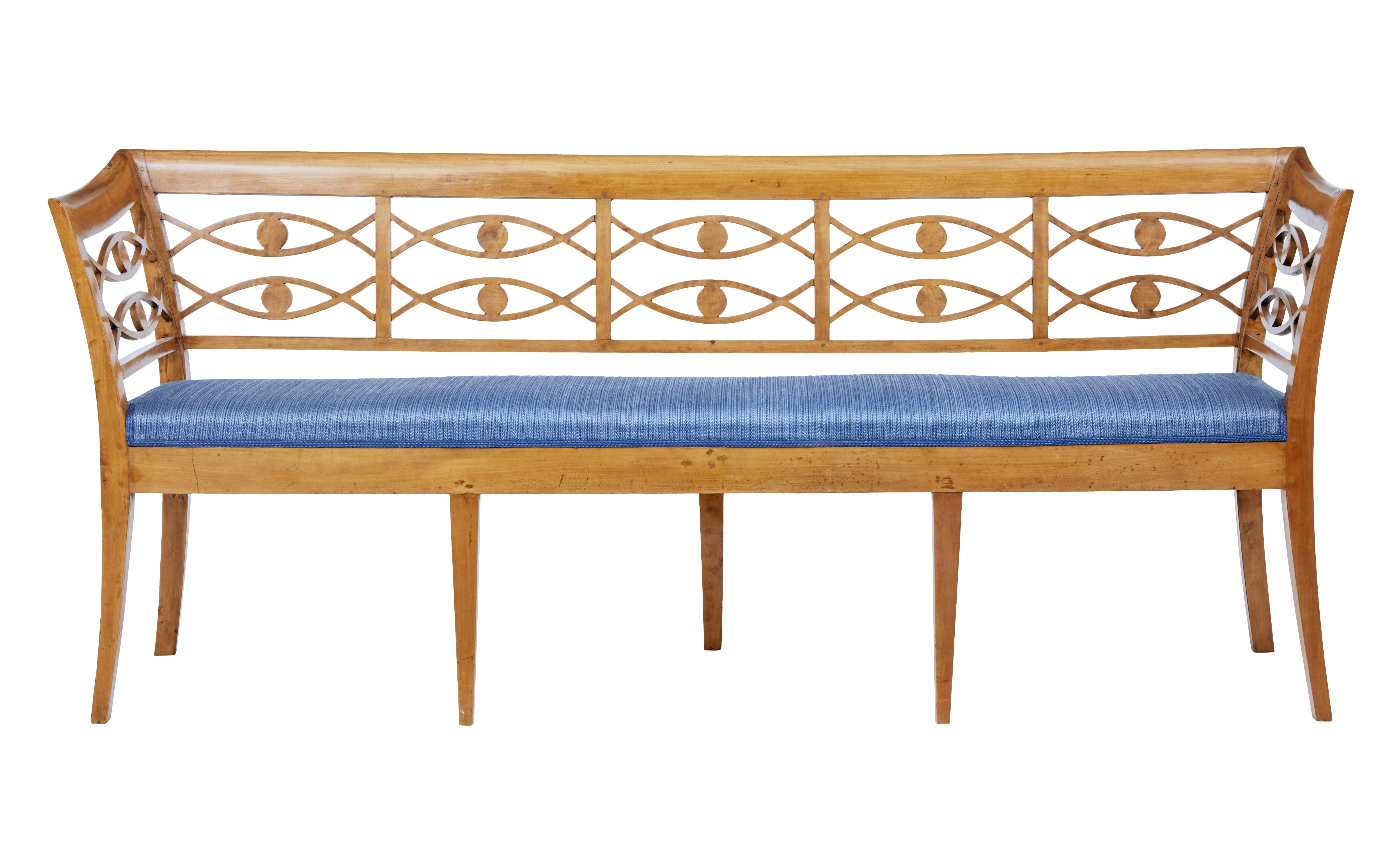 Elegant Swedish birch bench, circa 1890.

Shaped arms and back, with open panel fish like design in the arm and back rests. Rich birch color and patina. Standing on 7 tapered legs.

Re-covered seat in good condition.

Minor marks to