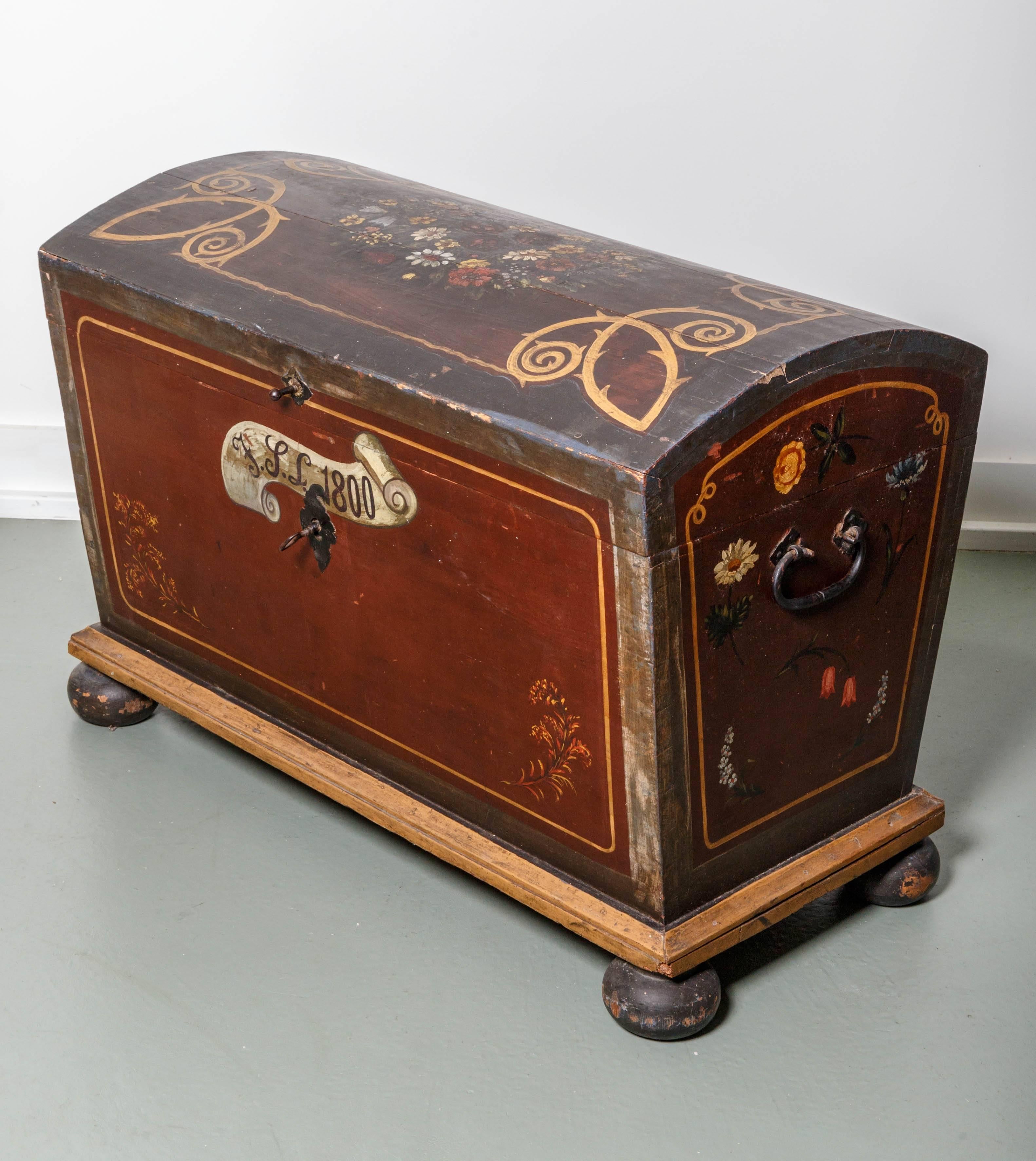 A large impressive early 1800s Scandinavian painted pine dome top trunk on bun feet. Original hardware and locking system with interior hinged candle box. Beautifully painted floral motif done in the late 19th century.