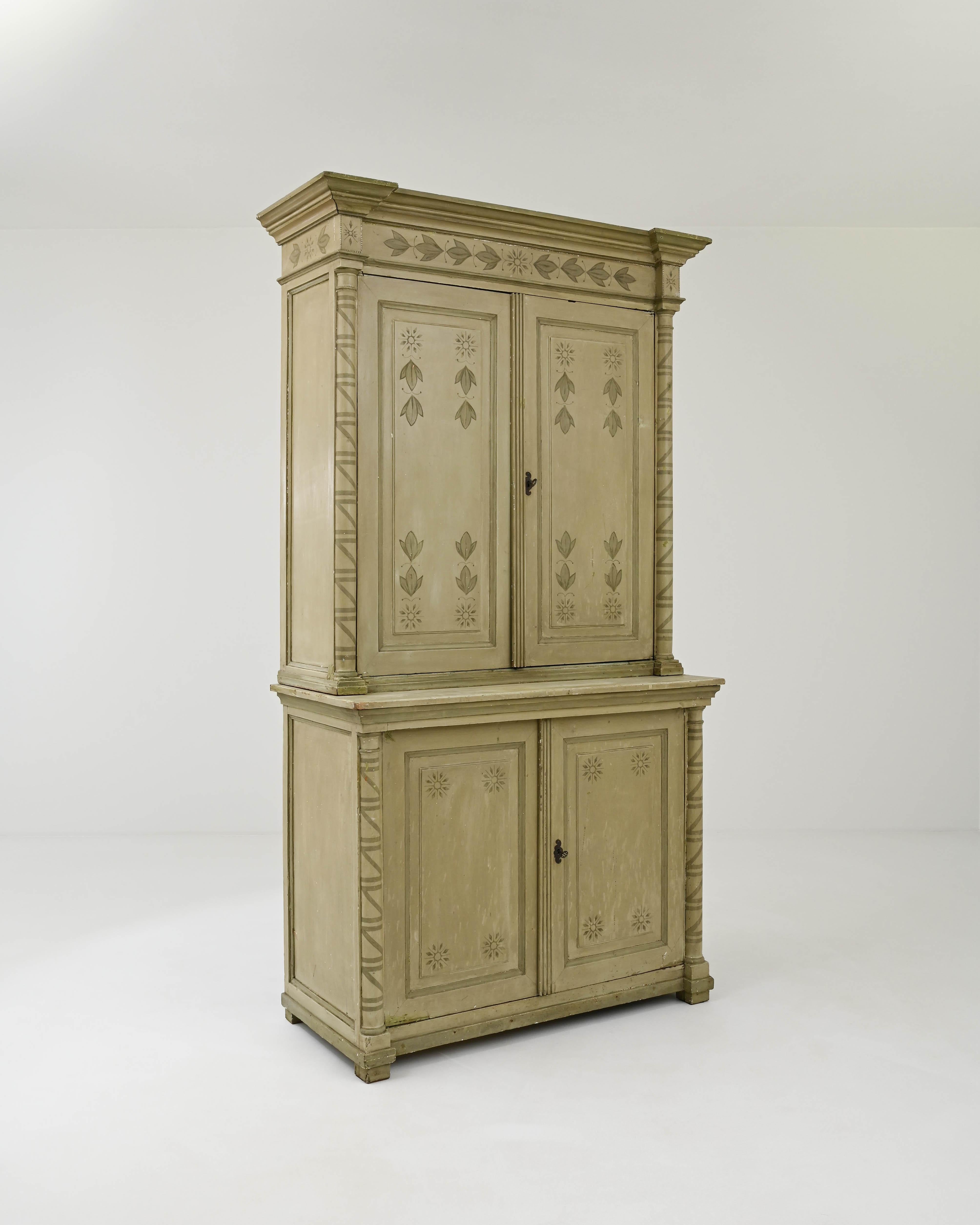 Flaunting a gorgeous olive hued patina, this wooded à deux corps giant was hand-crafted in Scandinavia during the 19th century. Masterfully carved elements, including the molded cornice, panels, columns, and the base, are complemented by charming