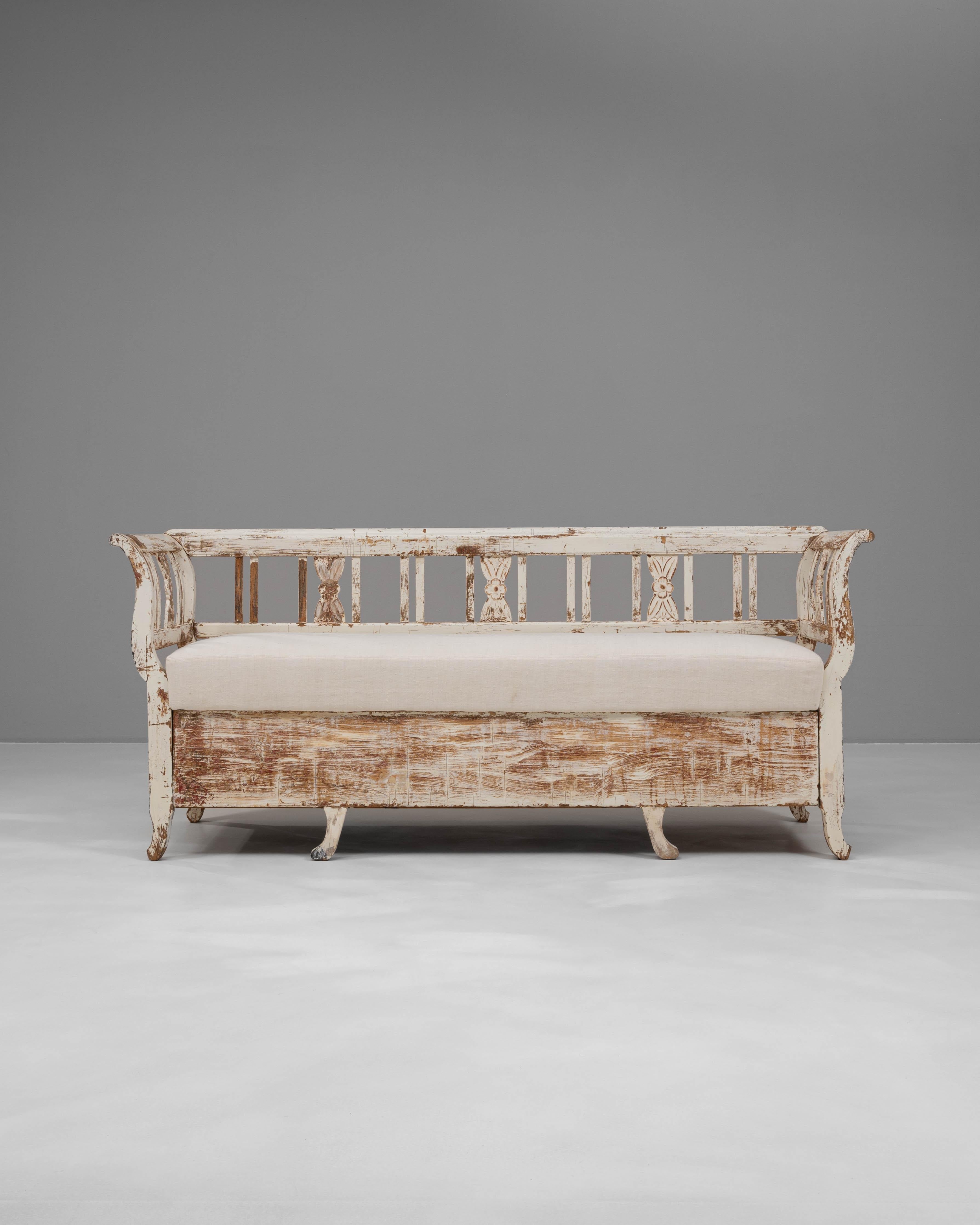 Questa panca imbottita scandinava del XIX secolo incarna il fascino tranquillo e l'artigianato caratteristico dei mobili rurali del Nord Europa. I braccioli graziosamente curvati, lo schienale a fuso aperto e i motivi decorativi intagliati