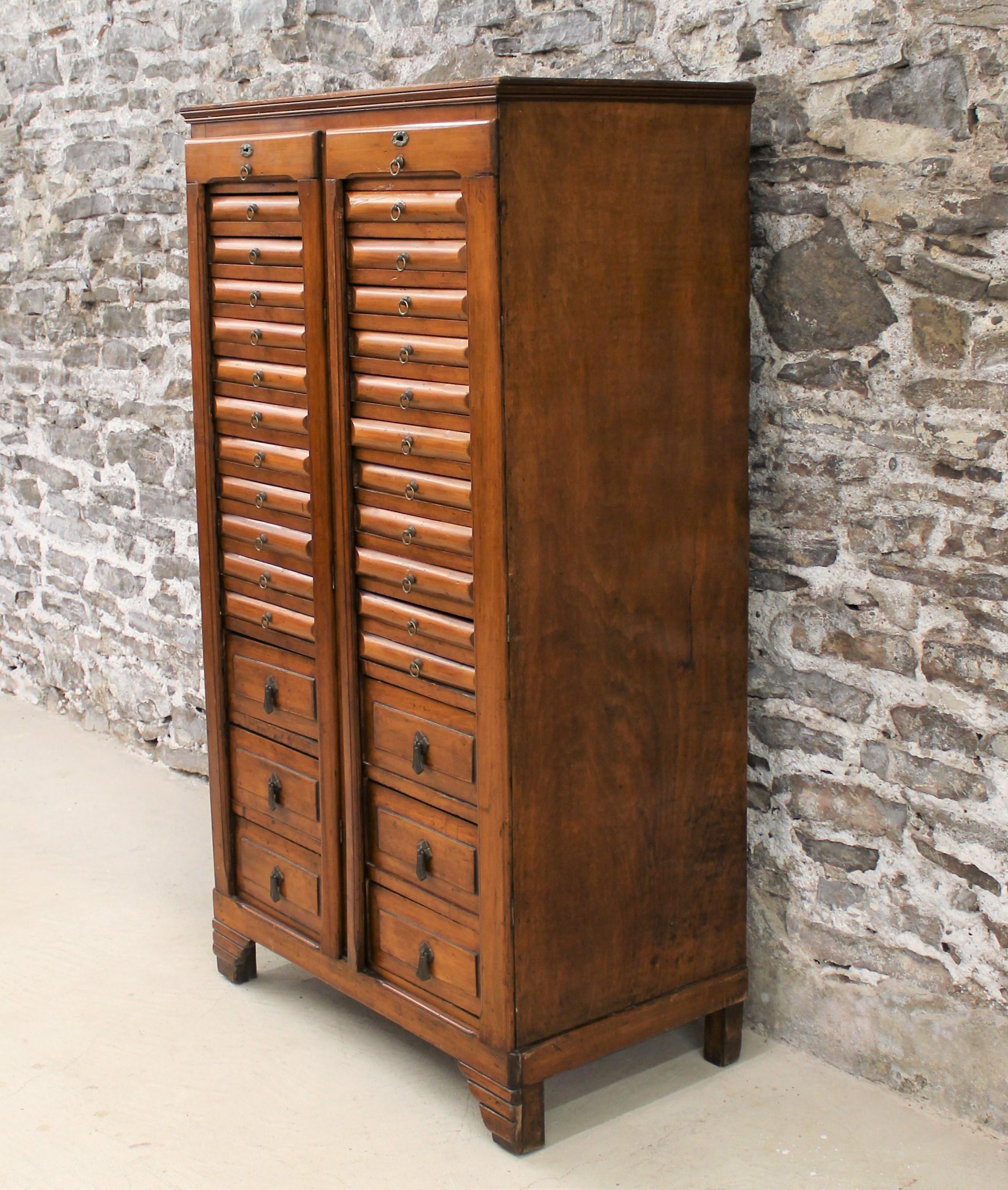 This unique specimen cabinet features eleven smaller drawers above three larger ones, all with brass pulls. In the manner of a Wellington chest.