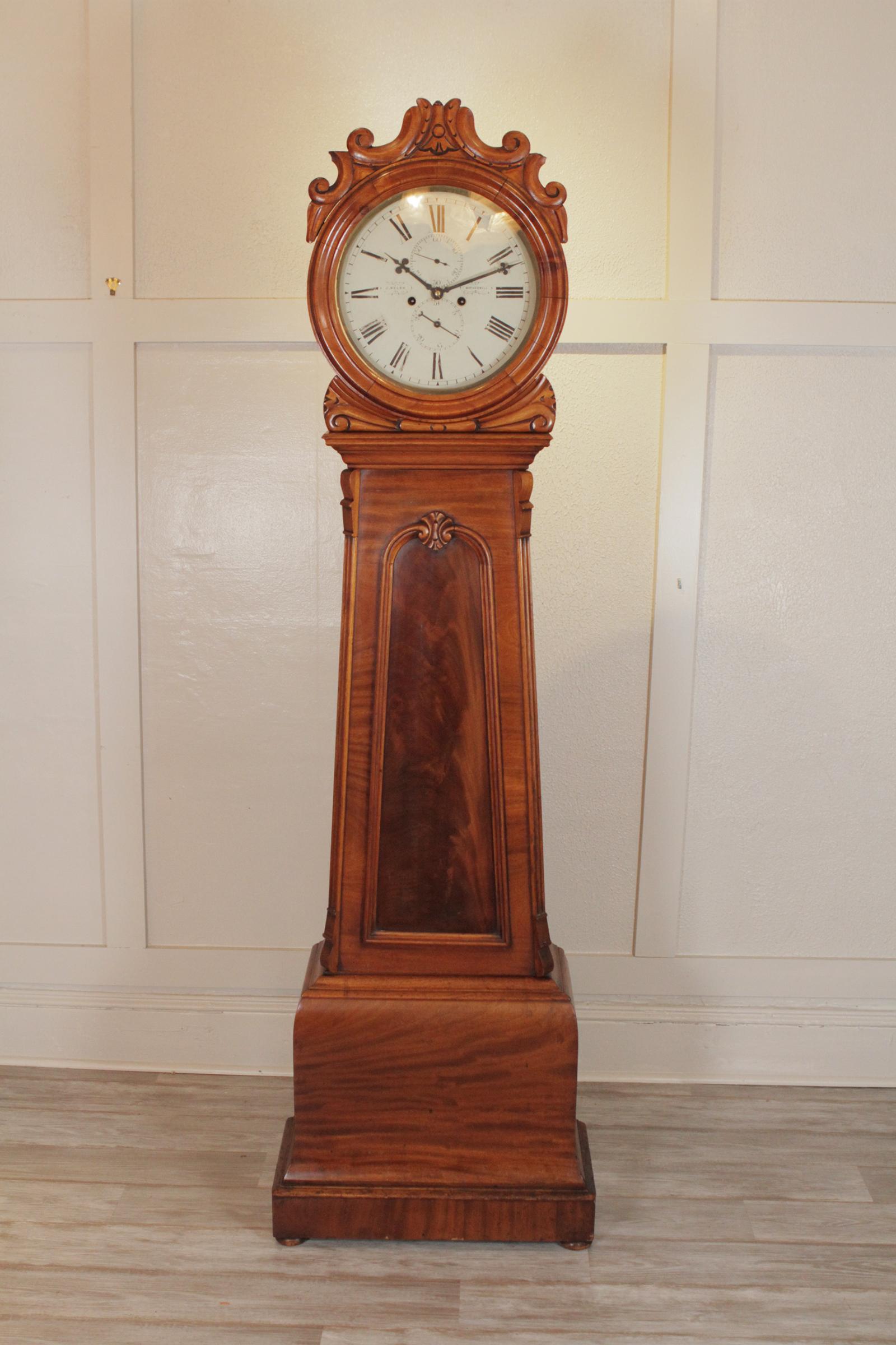 19th century Scottish Drum clock, hand-carved mahogany, with round face, tapering body and blind door with weights and pendulum behind. The clock strikes on the hour, in running condition but may need adjustment when transported. circa 1880