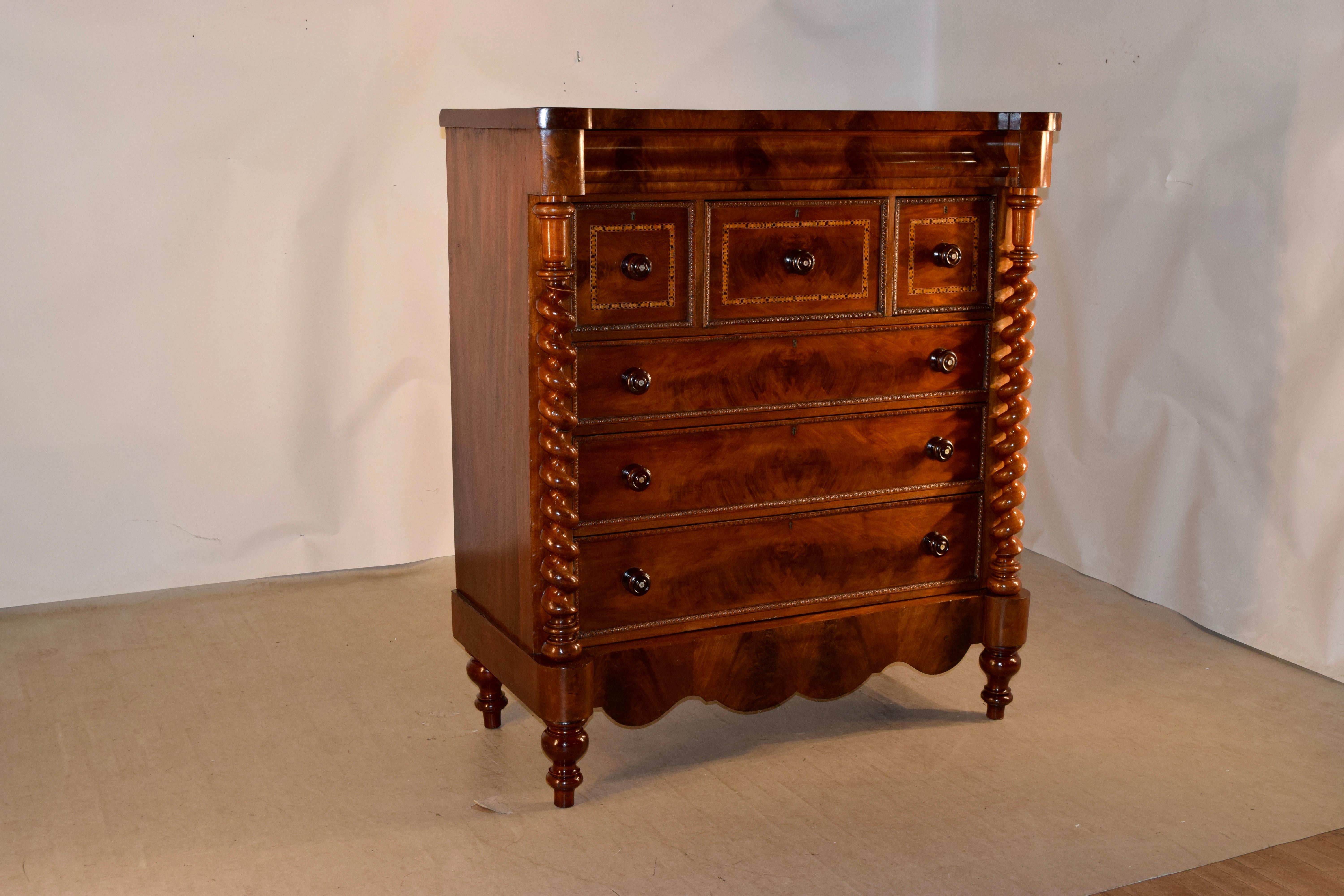 19th century large mahogany chest of drawers from England with a shaped top, following down to beautifully grained sides and a hidden top drawer in the molding, over three inlaid banded drawers over three larger drawers, which are flanked by hand