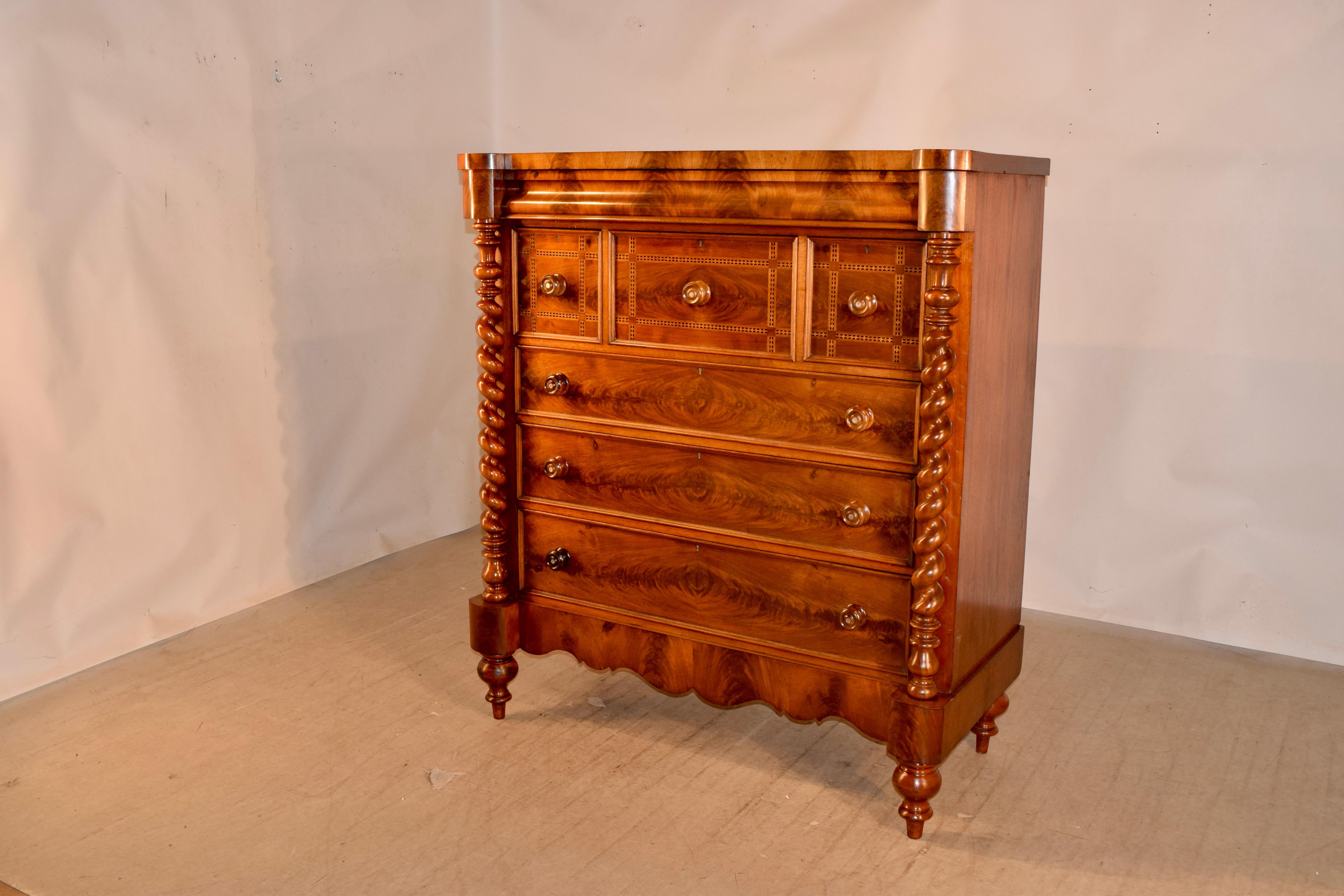 19th century large mahogany chest of drawers from Scotland with a shaped top, following down to simple, elegant sides and a hidden top drawer in the molding, over three inlaid banded drawers over three larger drawers, which are flanked by hand