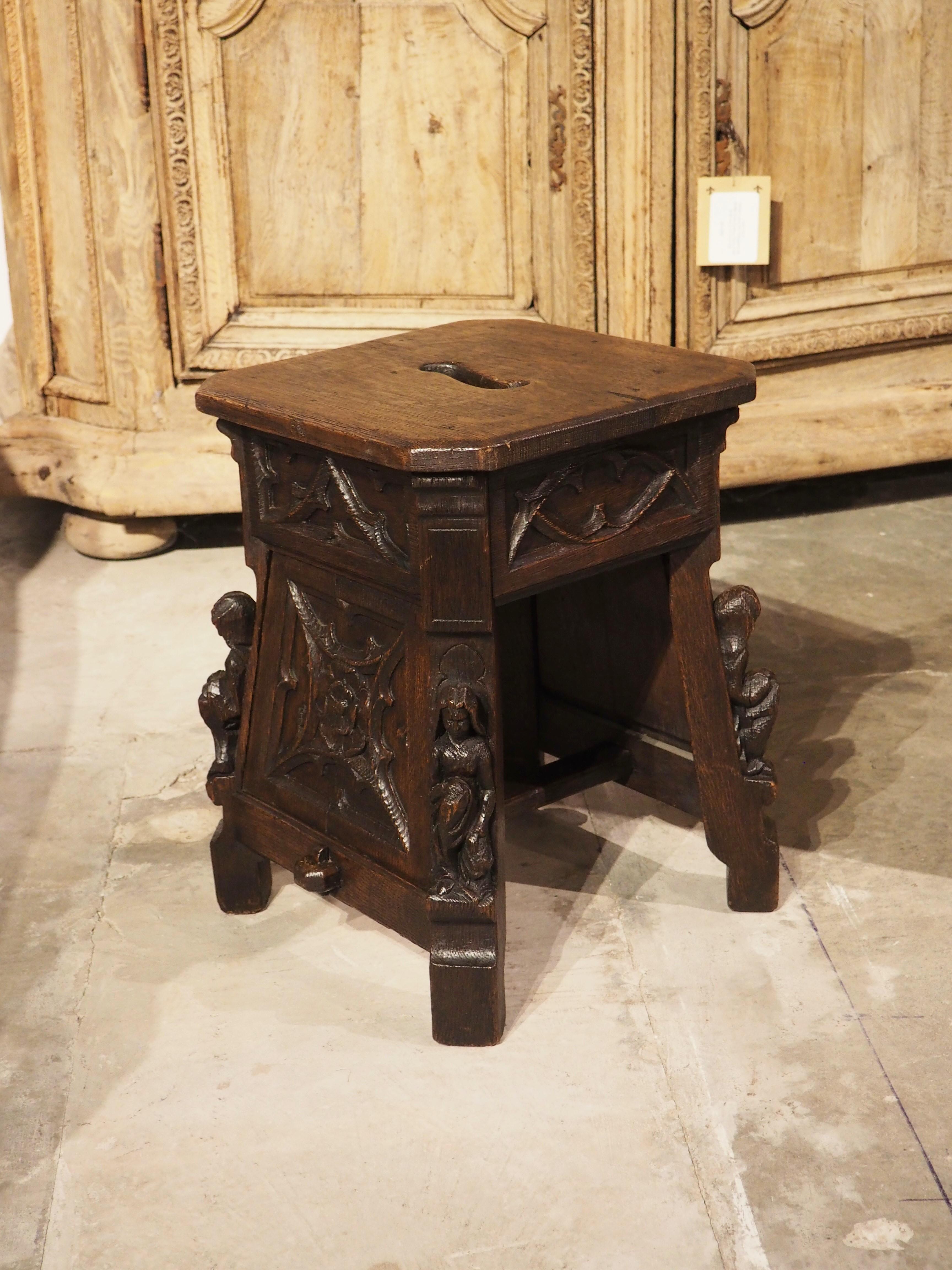 Hand-carved in France in the 1800’s, this oak tabouret stool was sculpted by an immensely talented menuisier in the Gothic style. A rectangular seat with canted corners has an elongated elliptic cutout in the center. Below each canted corner is a