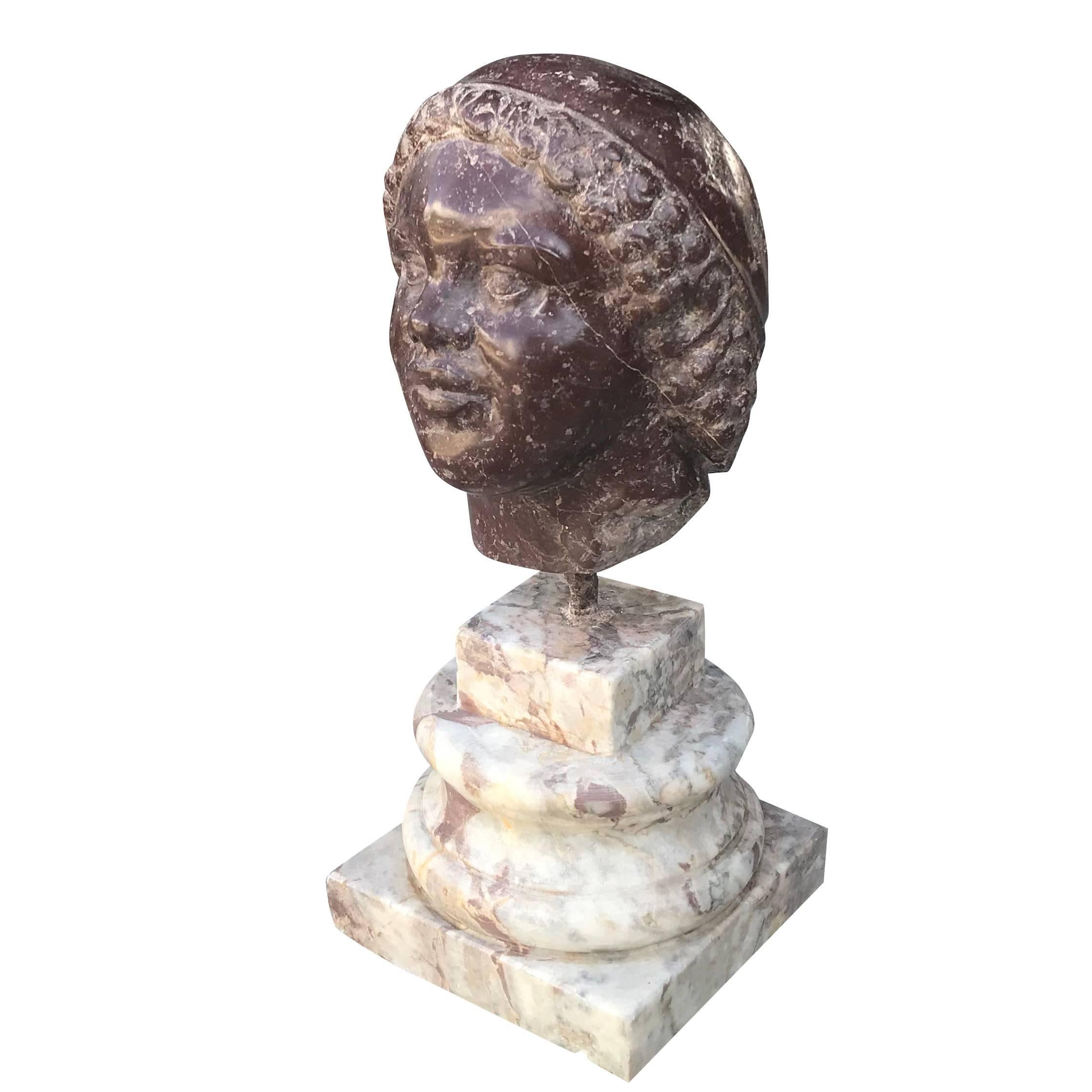 An antique Italian head sculptured in Porphyry sitting on a Carrara marble column with a square step base in the style of Benvenuto Cellini, in good condition. The Italian décor represents the Renaissance time period. Wear consistent with age and