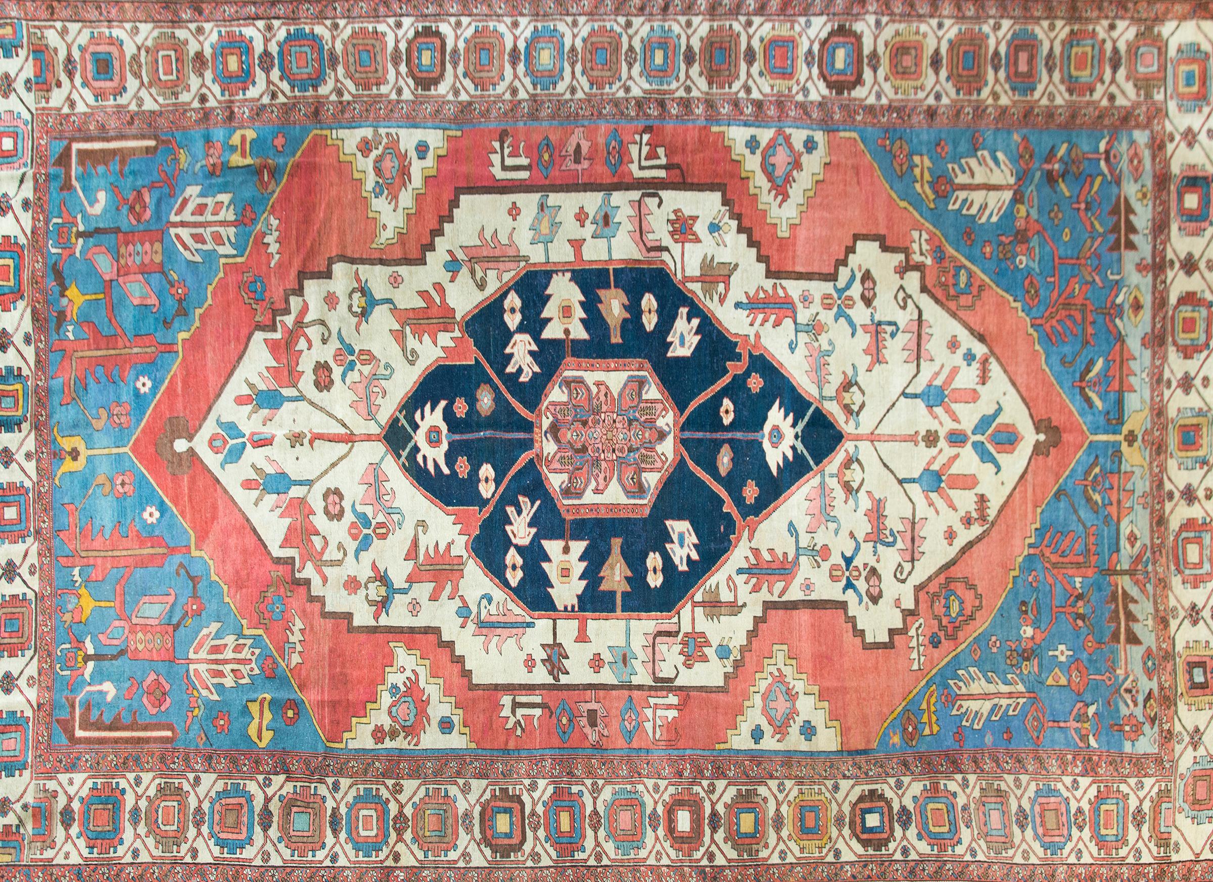 An outstanding late 19th century Persian Serapi rug with the most beautiful central medallion with a stylized floral and leaf pattern woven in wonderful and brilliant crimsons, light indigos, white, and gold, set against a dark indigo background,