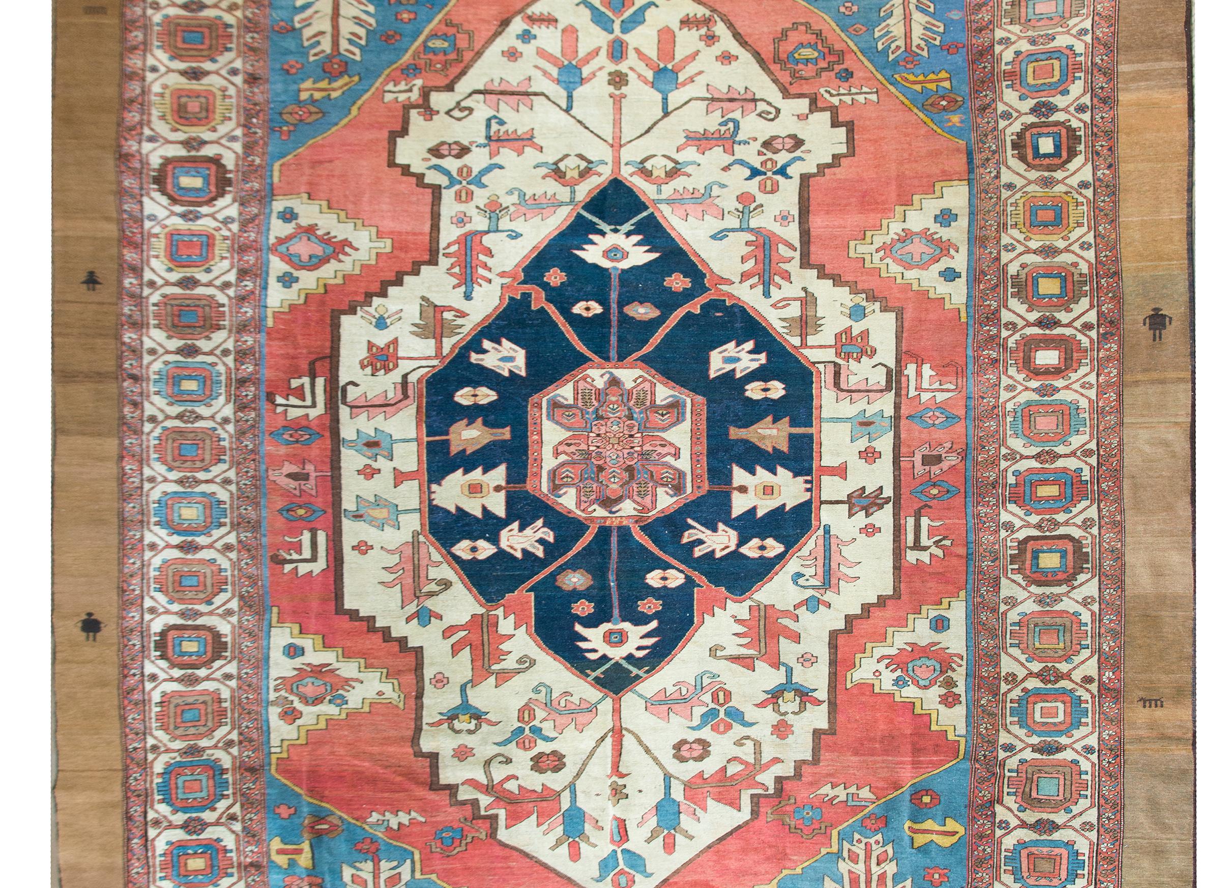 An outstanding late 19th century Persian Serapi rug with the most beautiful central medallion with a stylized floral and leaf pattern woven in wonderful and brilliant crimsons, light indigos, white, and gold, set against a dark indigo background,