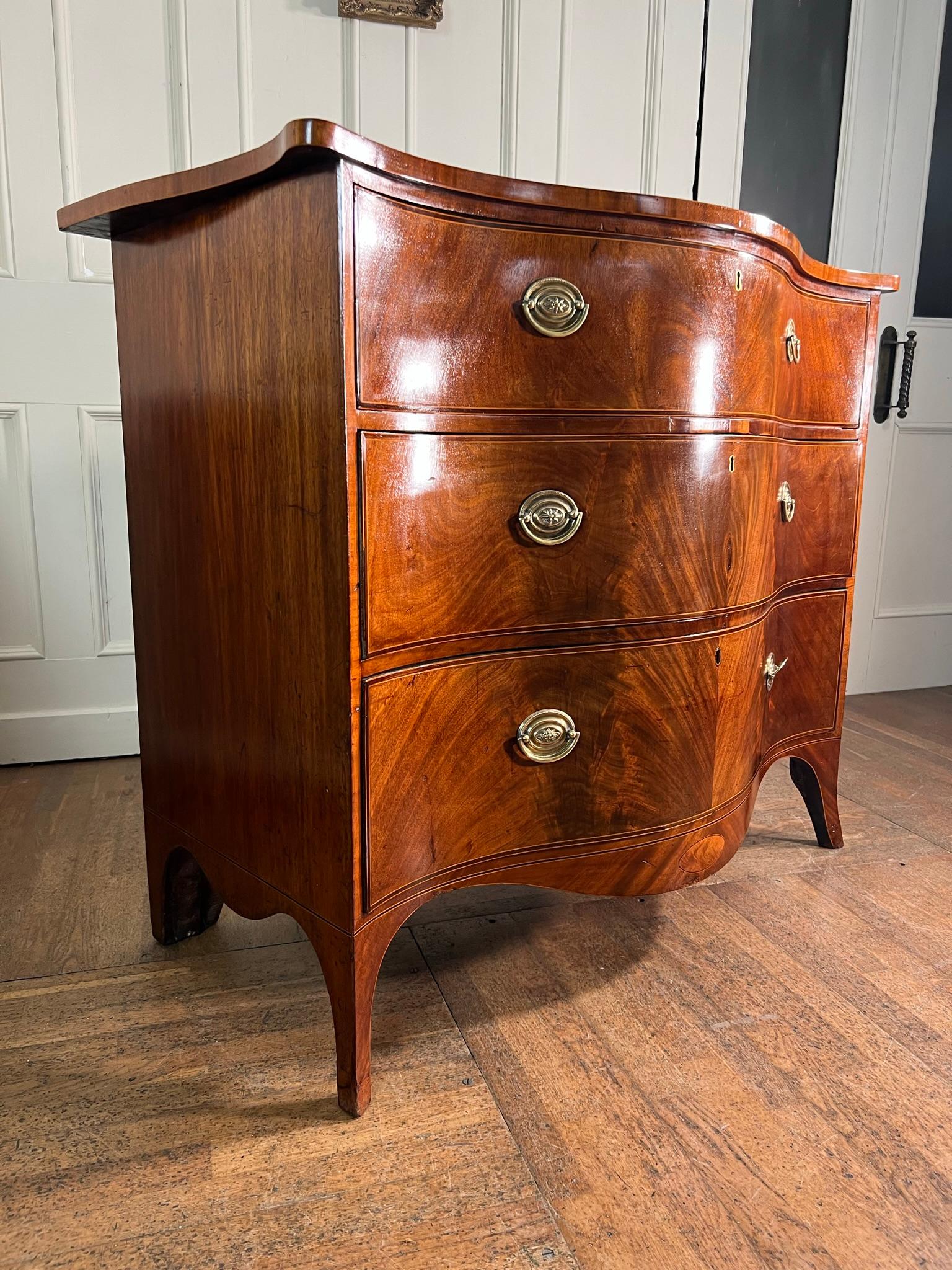 Well figured mahogany serpentine chest of drawers from the George III period.

Raised on splay legs with flowing apron.

Box and ebony stringing detail, minor veneer repair to the front as pictured.

Working drawer locks with original