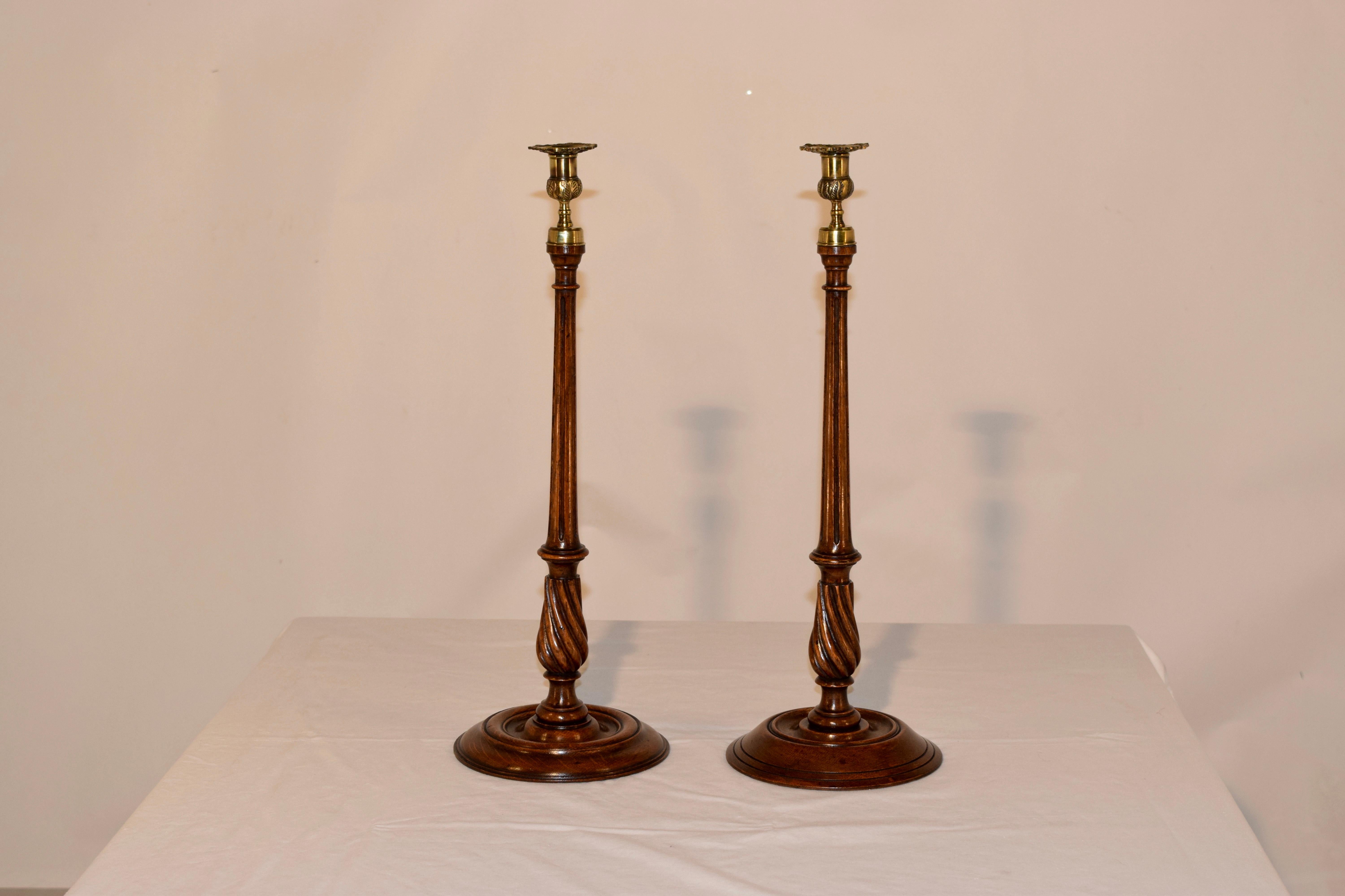19th century set of two tall candlesticks with hand cast brass candle cups over hand turned fluted and twist reeded stems over hand turned bases, which are slightly different. Great height.