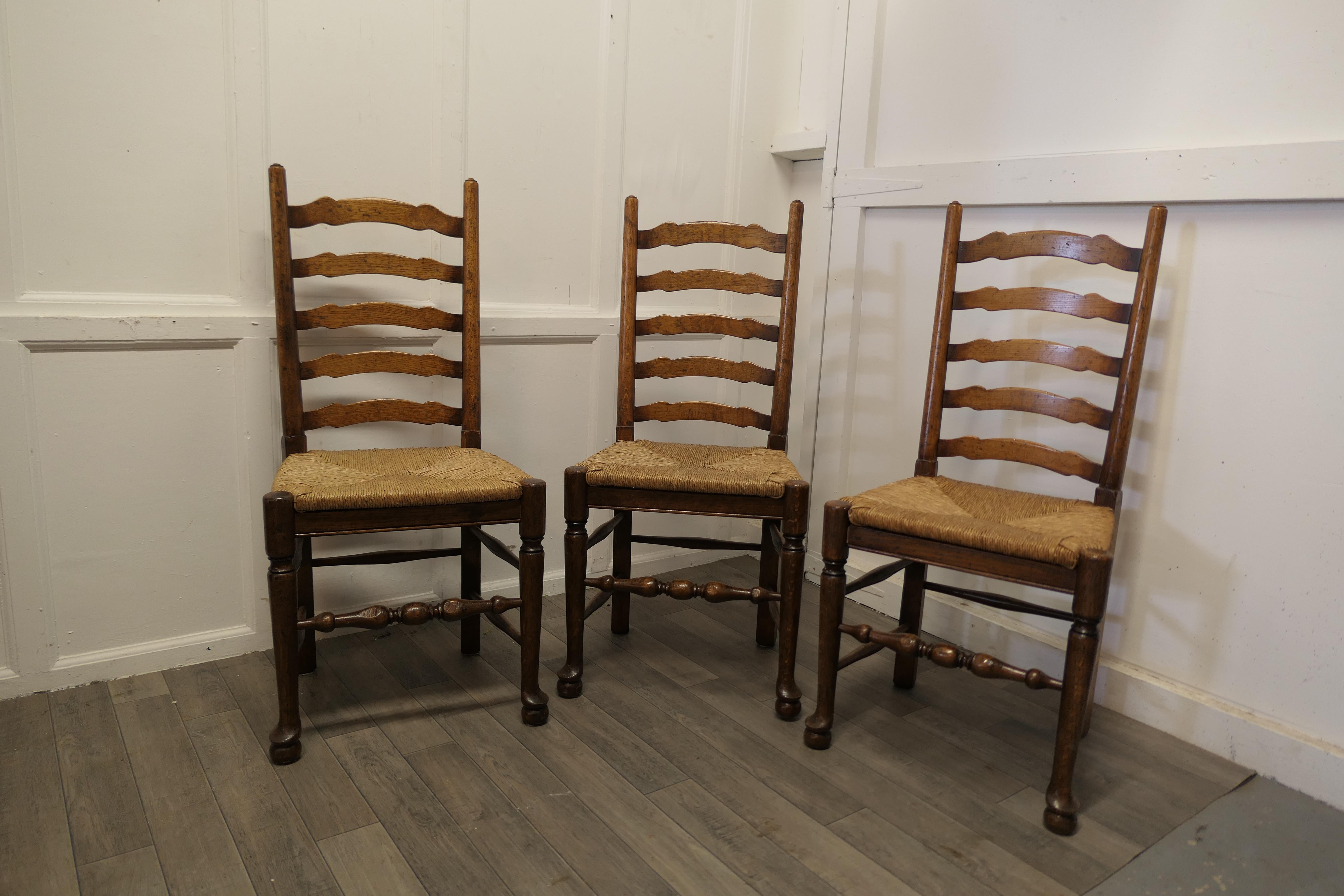 19th century Set of 3 farmhouse ladder back dining chairs.

This very attractive set of heavy Oak chairs with a wavy ladder back in the Georgian style, with turned stretchers and chunky pad feet
The chairs have a delightful country look with a